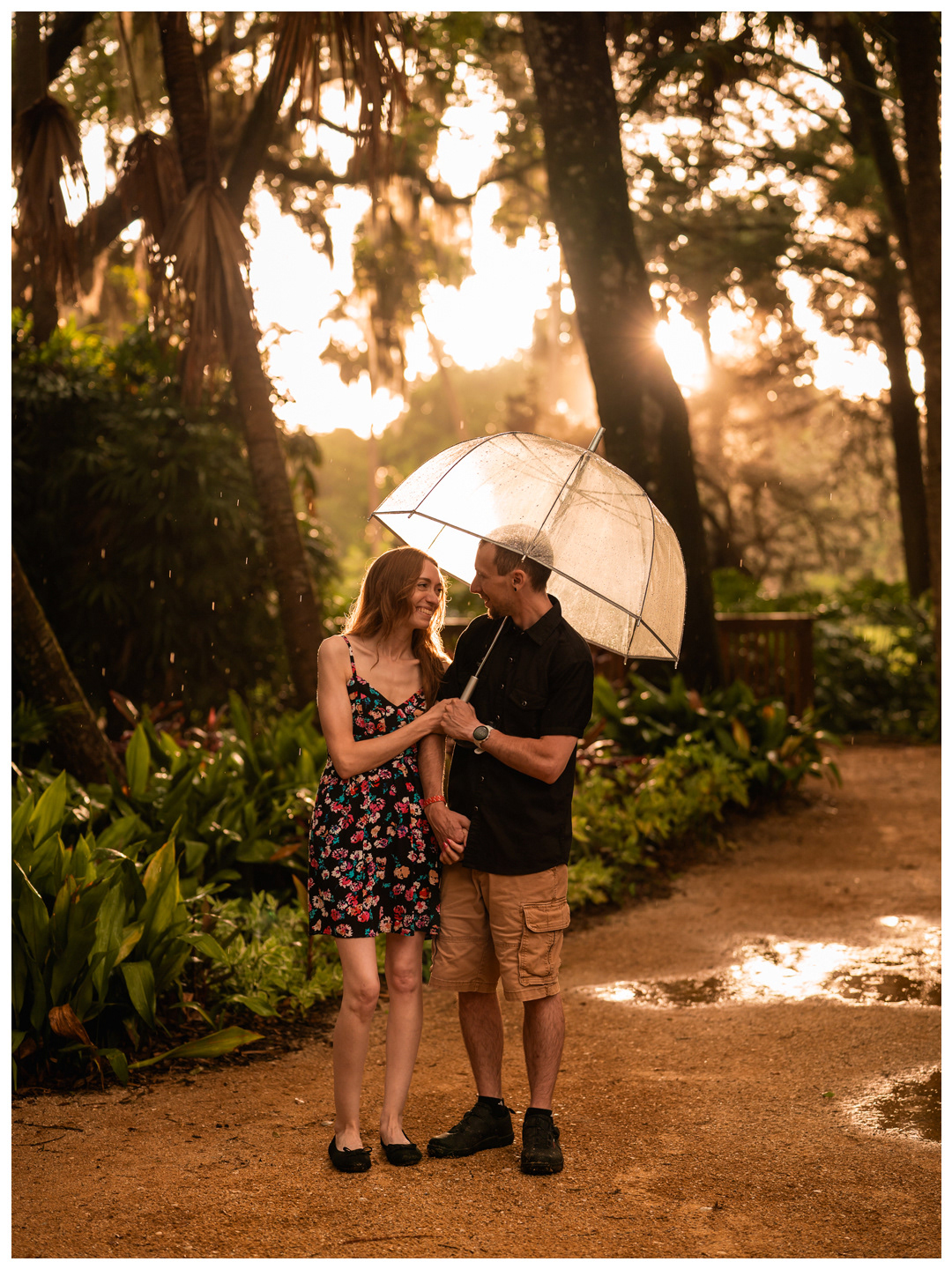 Couple standing together beneath an umbrella on a sunlit path at Washington Oaks Gardens.