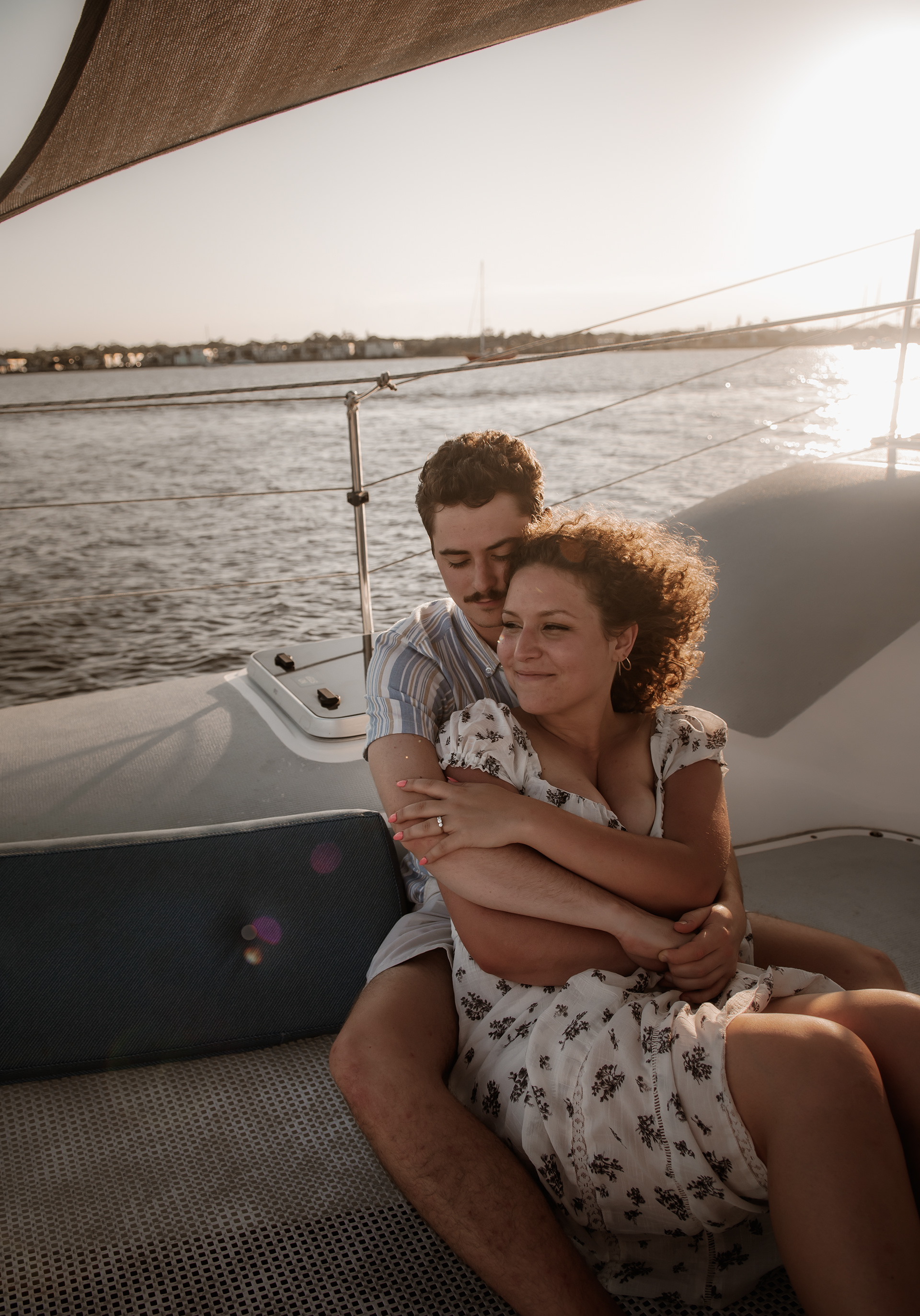Couple cuddling on a sailboat during a Daytona Beach engagement photo session