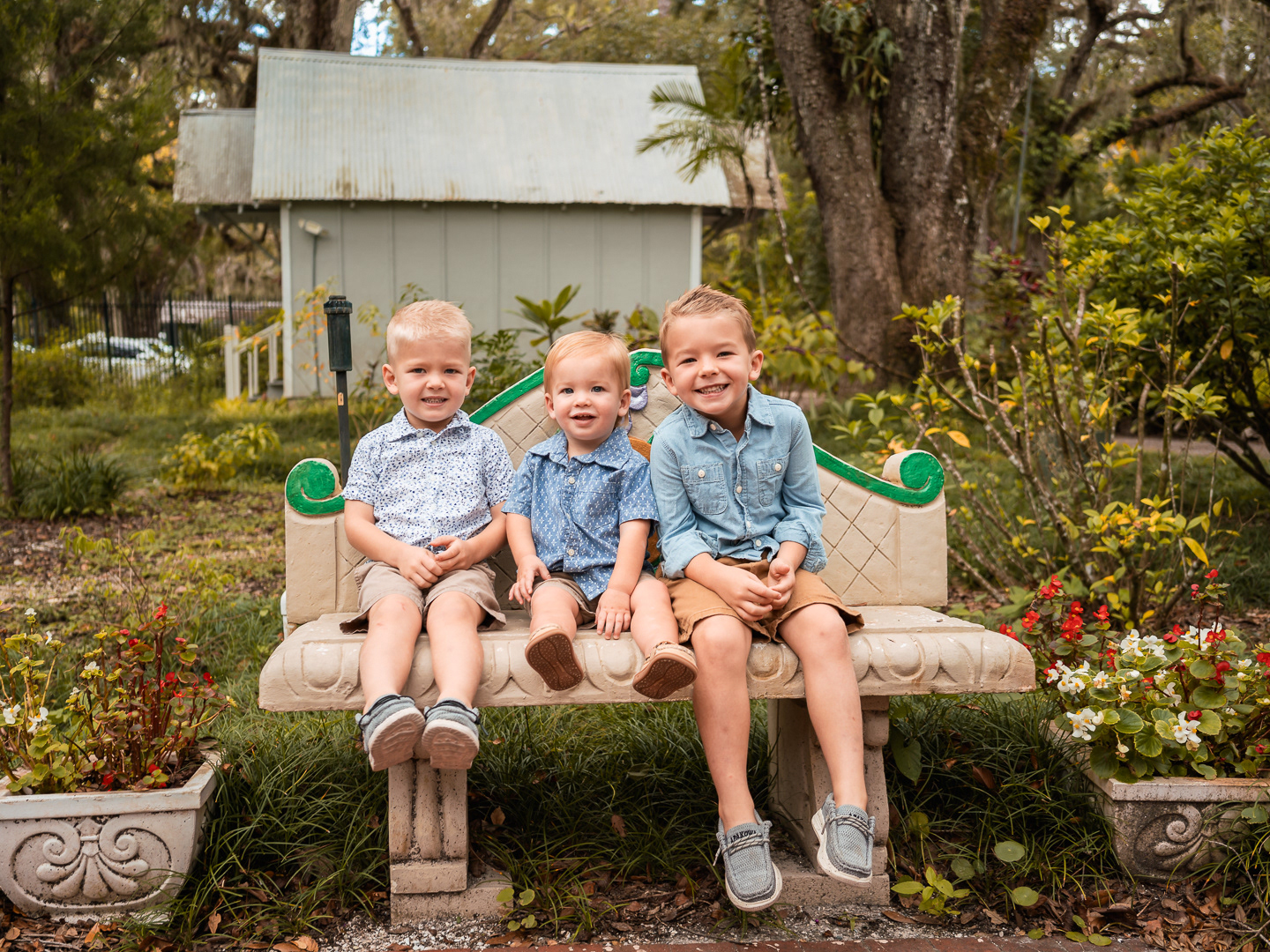 Three brothers sitting together on a garden bench at Dunlawton Sugar Mill Gardens during family photos in Port Orange, Florida