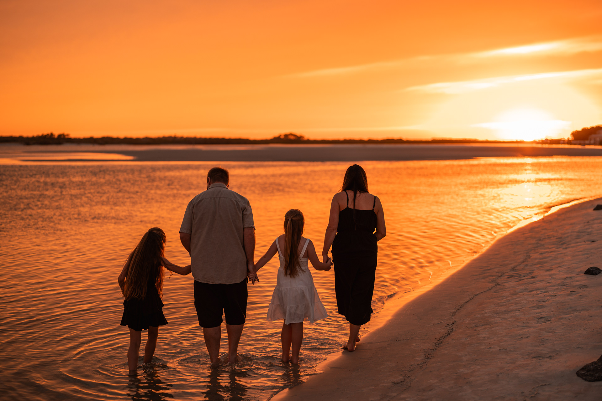 Family walking along the water at Ponce Inlet Beach during a sunset family photography session.