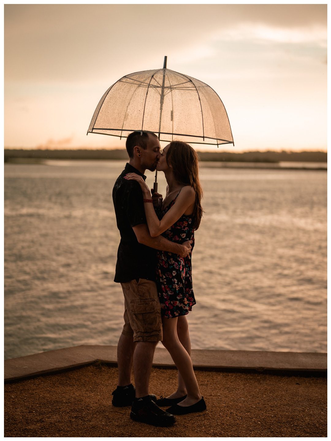 Couple kissing under an umbrella along the waterfront during a Washington Oaks Gardens photo session