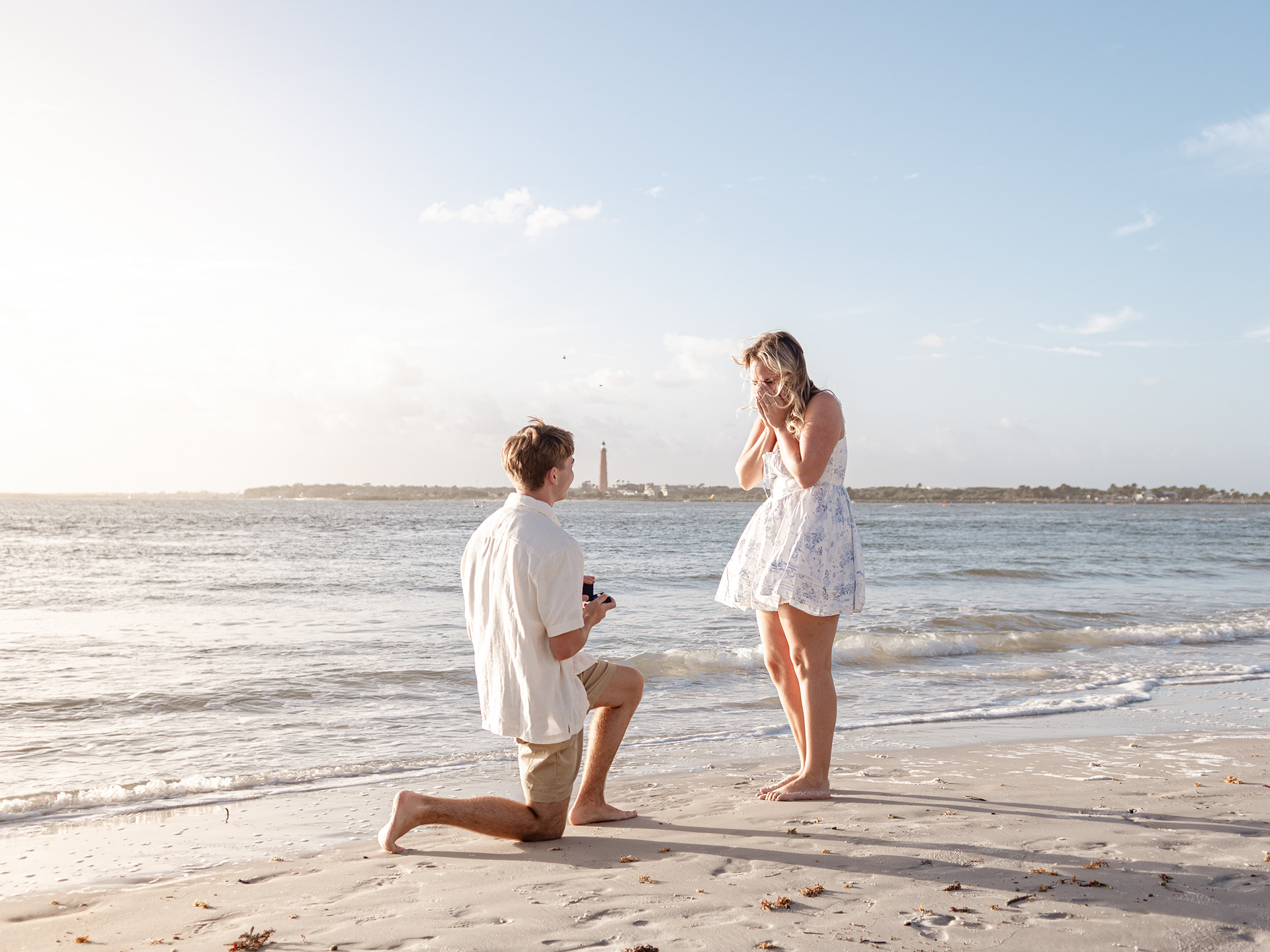 Beach proposal in New Smyrna Beach, Joey kneeling in the sand while asking Lexi to marry him at sunset.