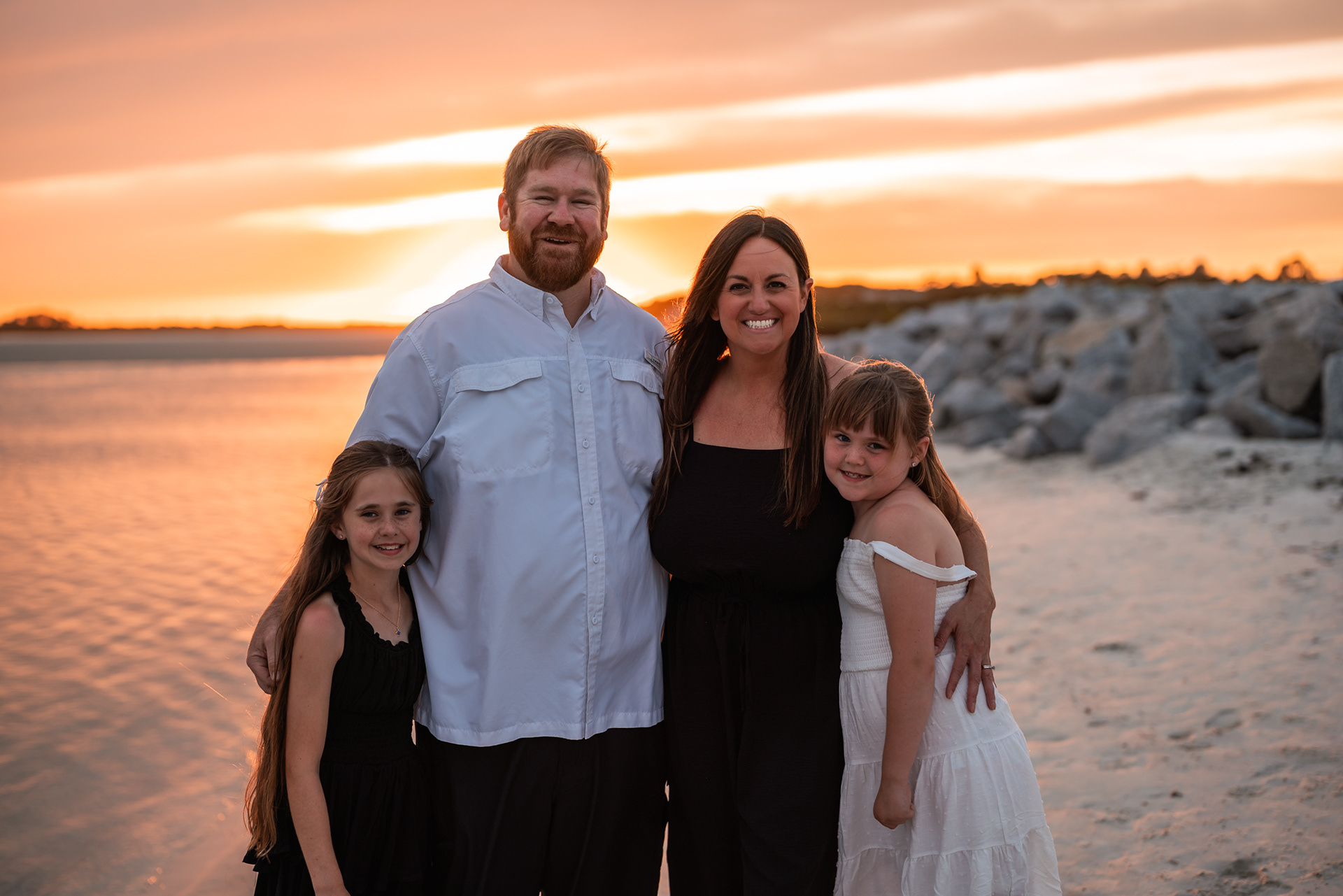 Family smiling together during a beach photography session at Ponce Inlet in Volusia County.