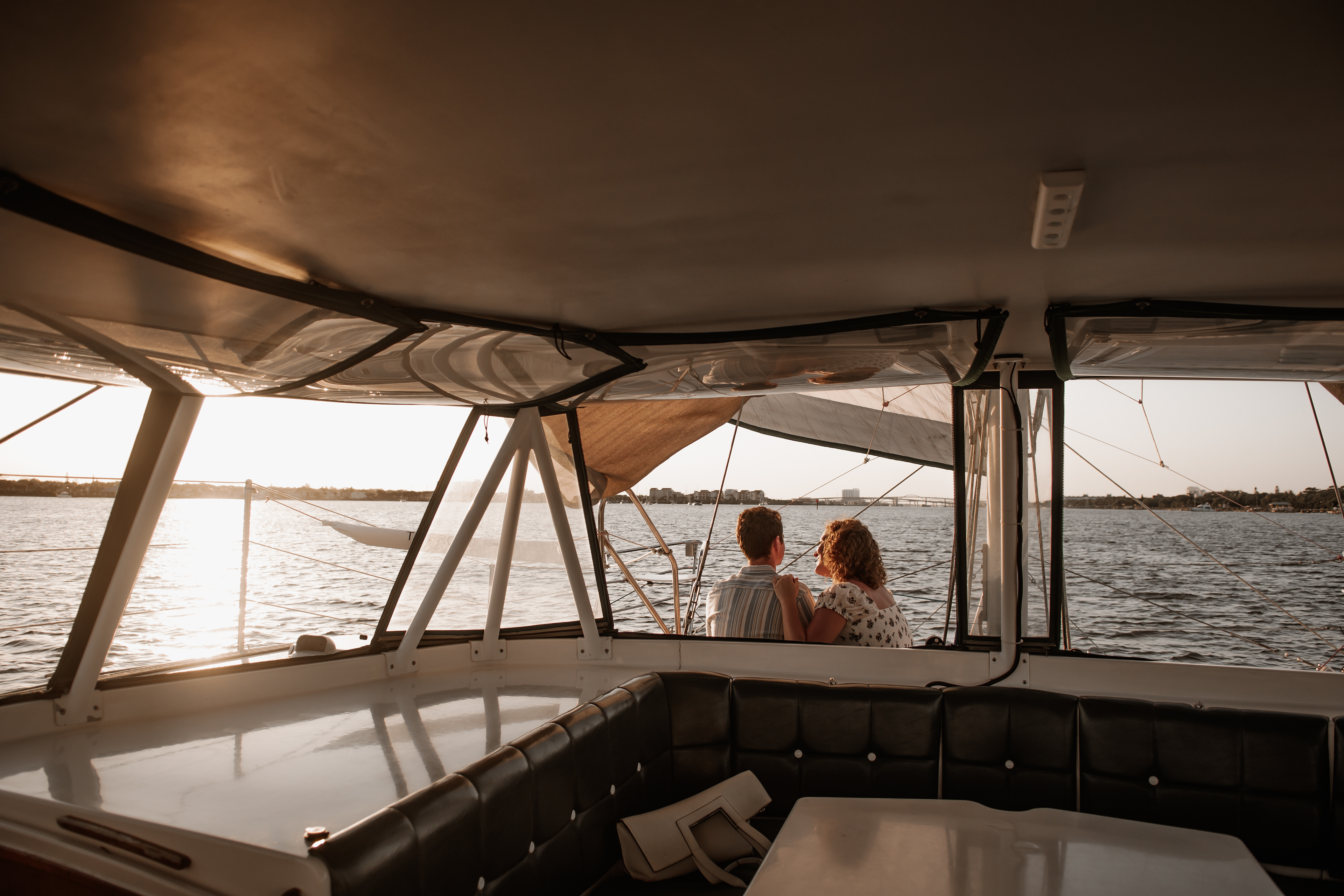 Wide sailboat engagement photo with couple sitting together and water view in Daytona Beach