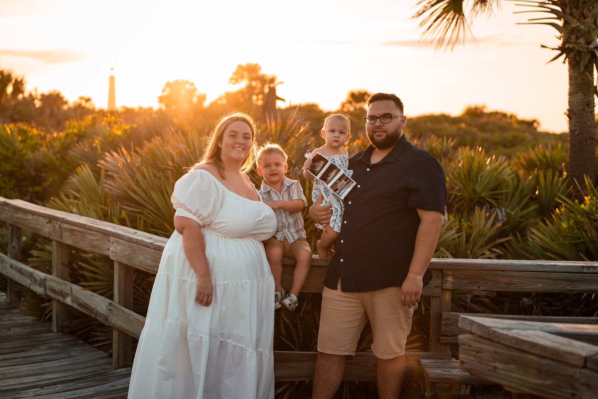 Ponce Inlet family photos on boardwalk with parents and children at sunset in Florida