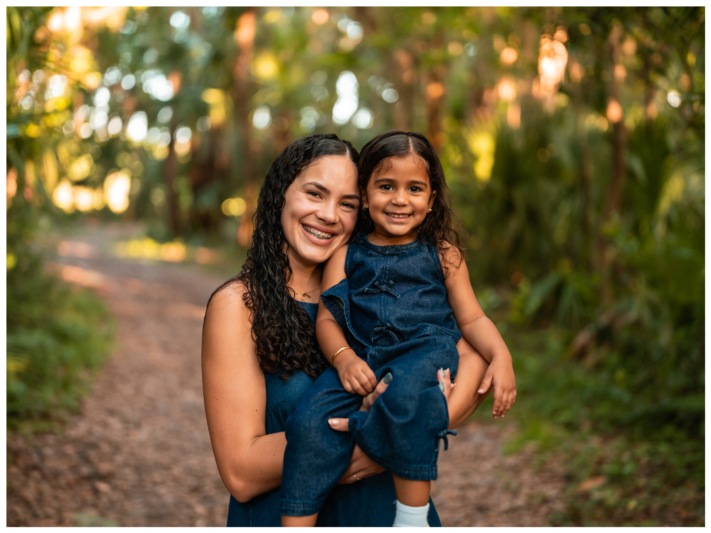 Mother holding daughter during family photos on trail at Buschman Park