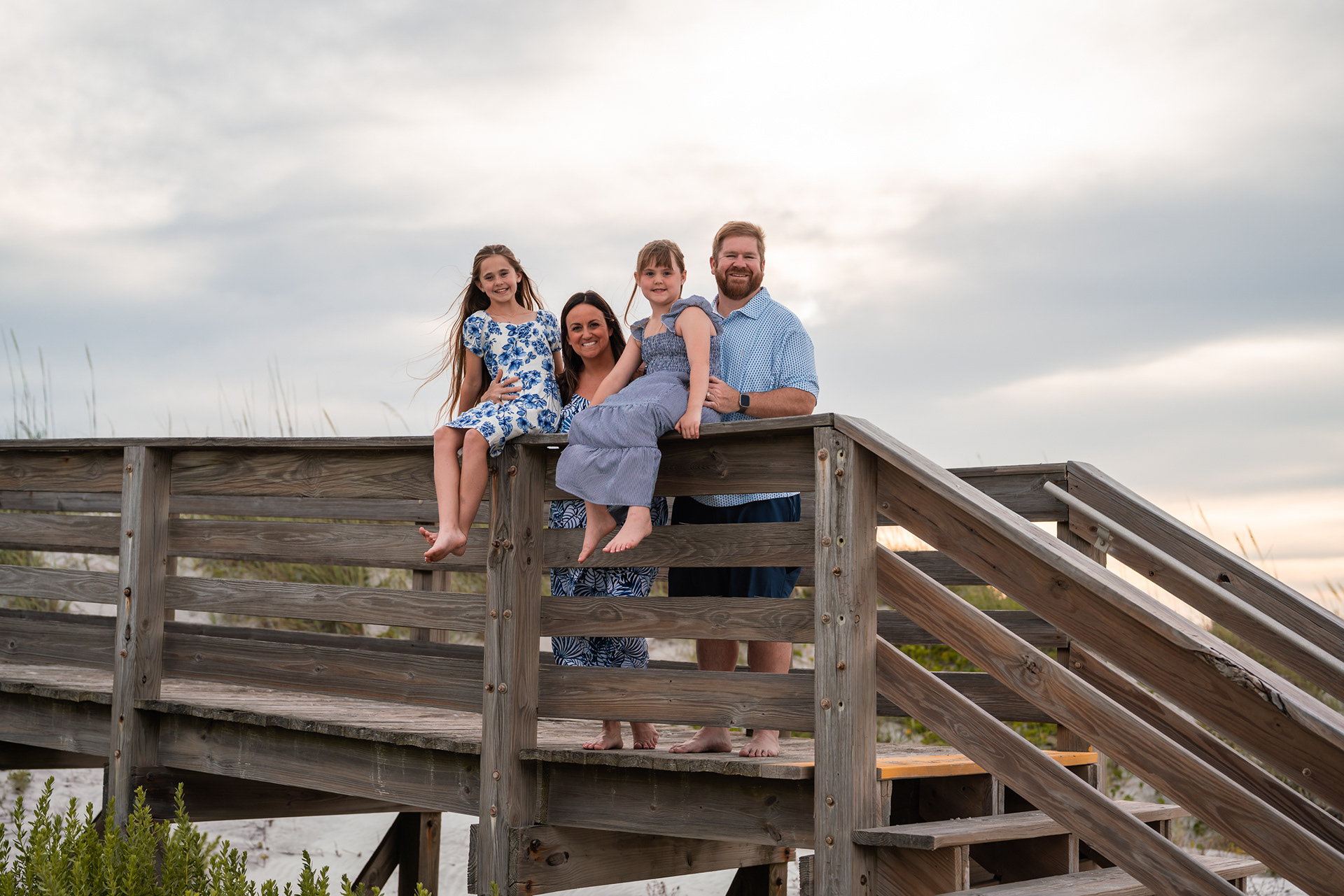 Family sitting together on the beach boardwalk during a Ponce Inlet family photo session.