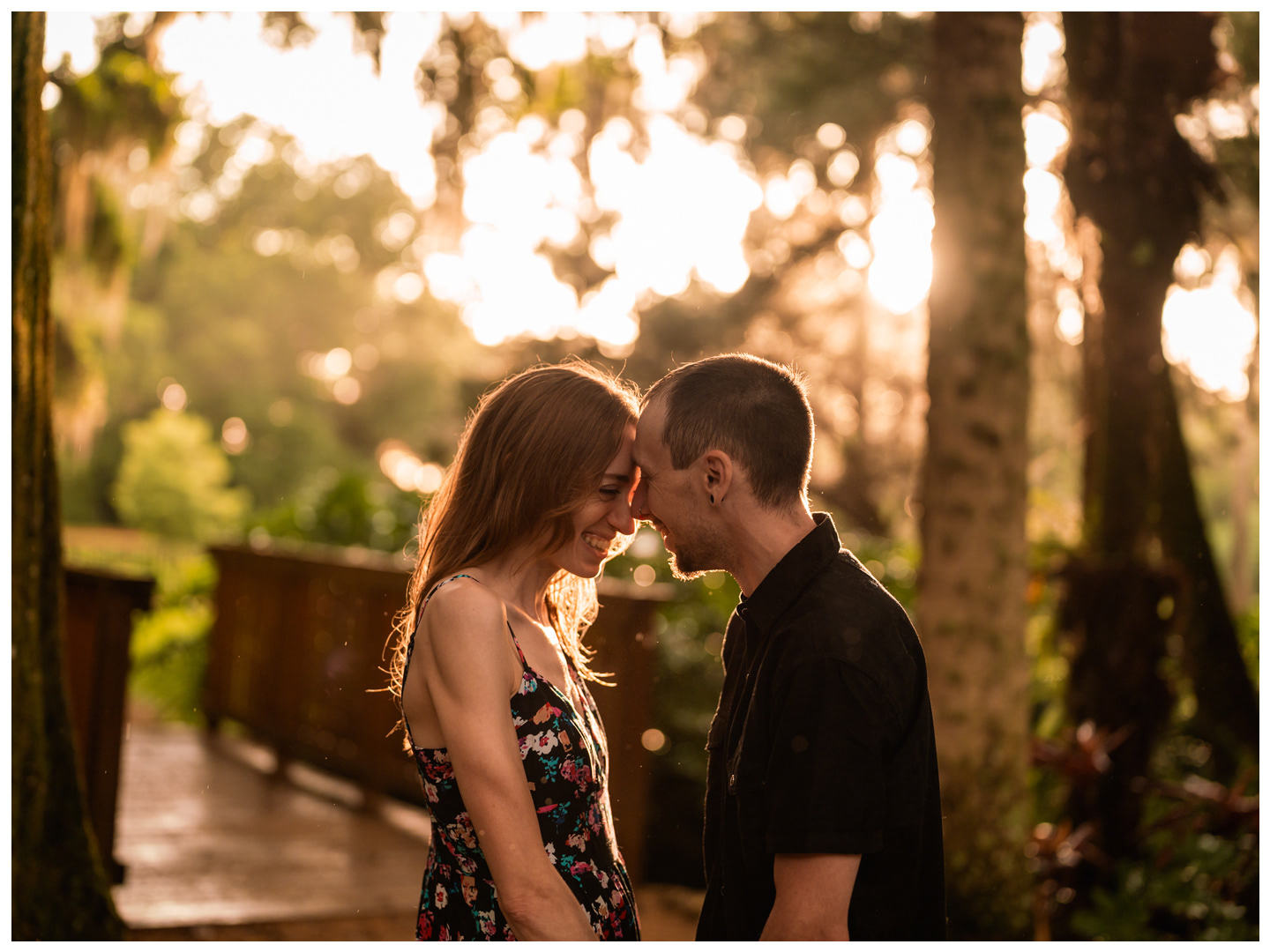 Couple touching foreheads near a wooden walkway during a Washington Oaks Gardens couples photo session.