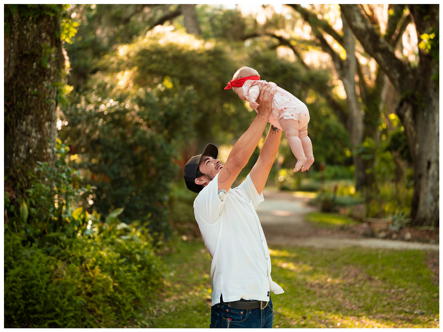 Father lifting baby during family photos at Dunlawton Sugar Mill Gardens in Port Orange Florida