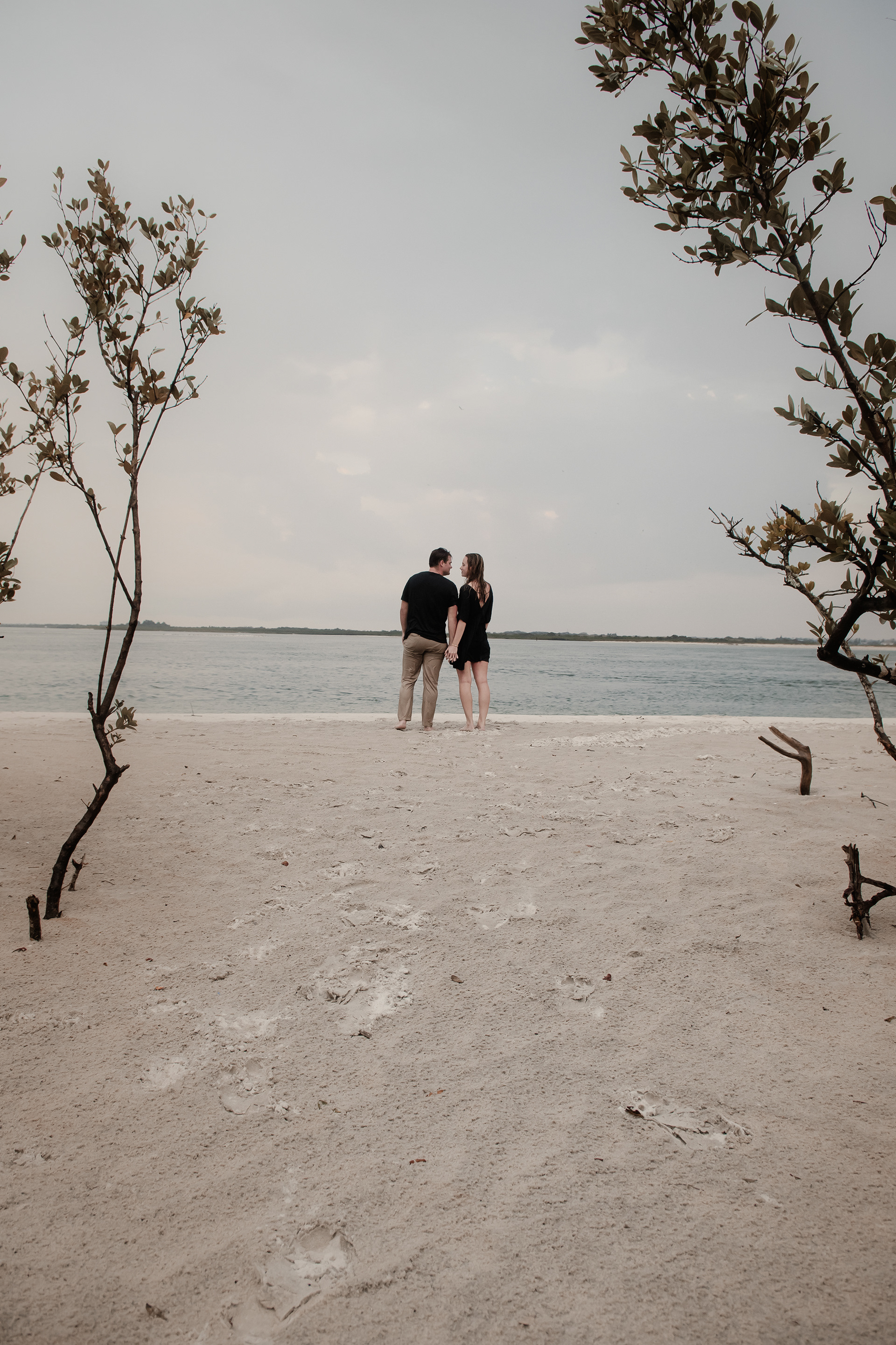 Ponce Inlet engagement photos with couple walking on the beach near the water and coastal trees