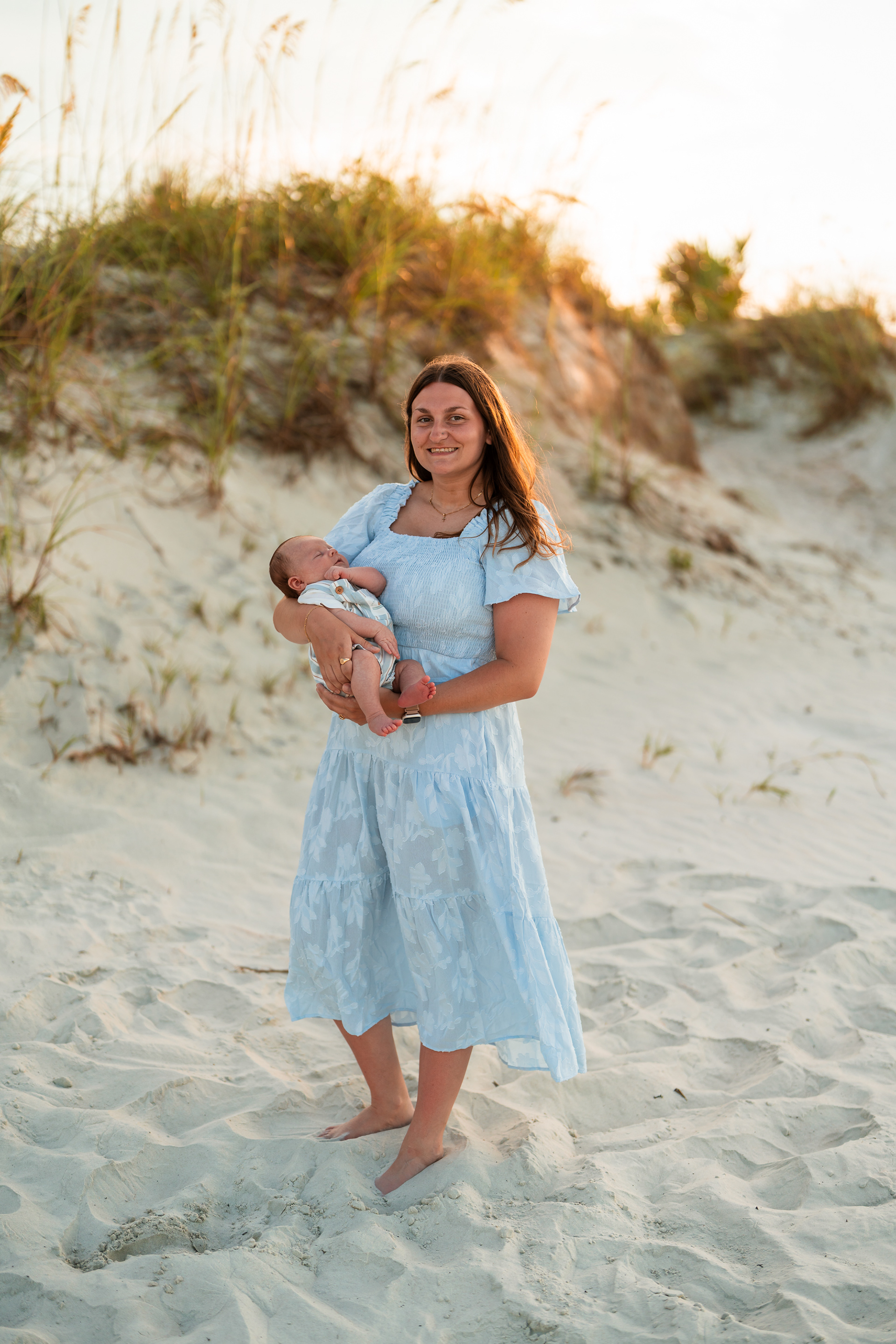 Mother holding her baby in the dunes during a family photo session at Ponce Inlet Beach.