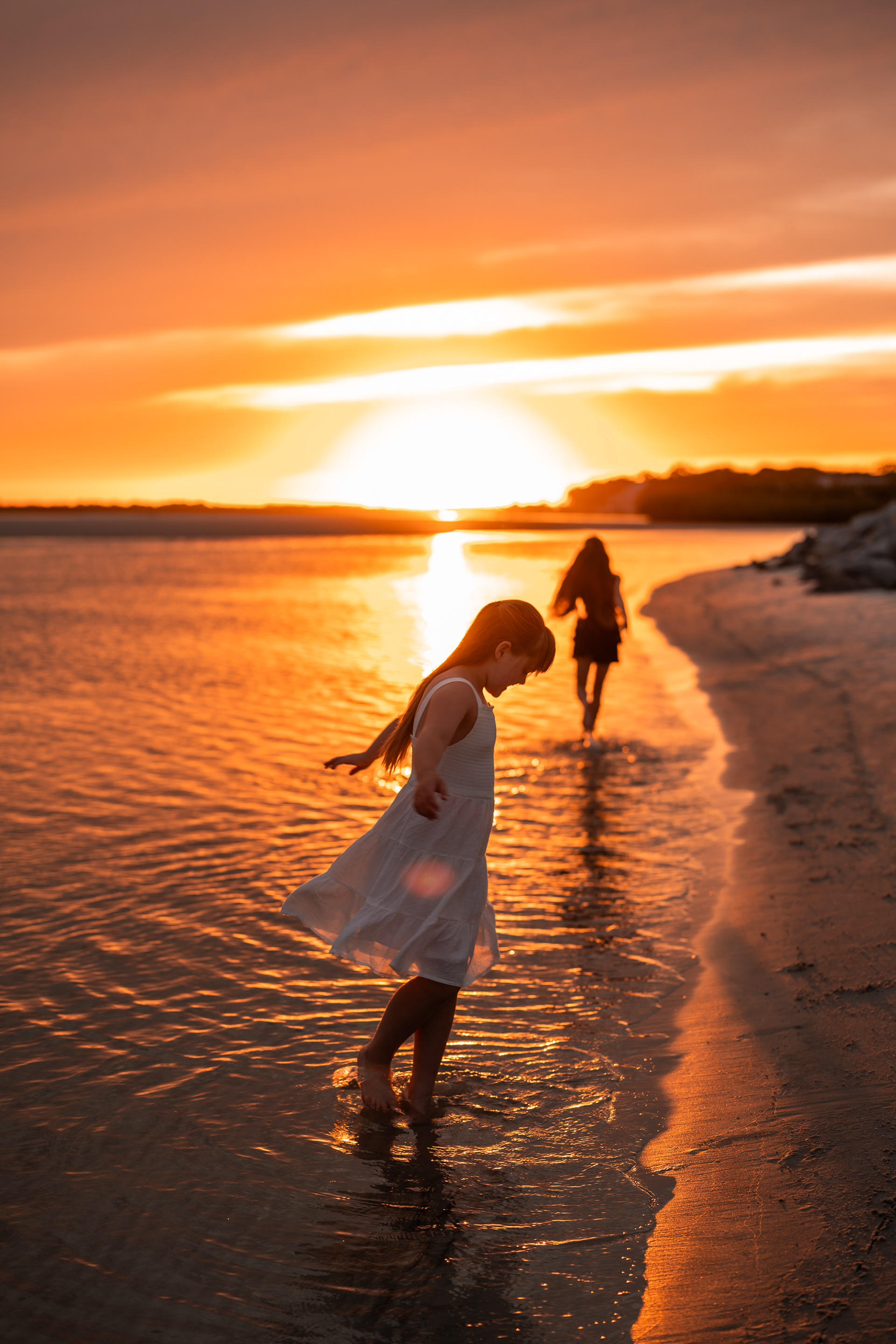 Child standing in the shallow water at sunset during a beach photo session in Ponce Inlet.