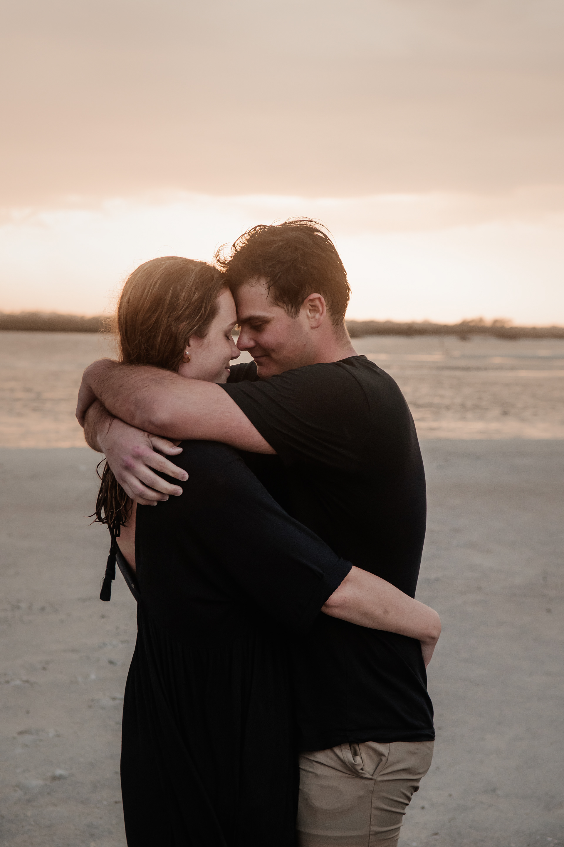 Candid engagement photo of couple hugging on the beach at Ponce Inlet Florida