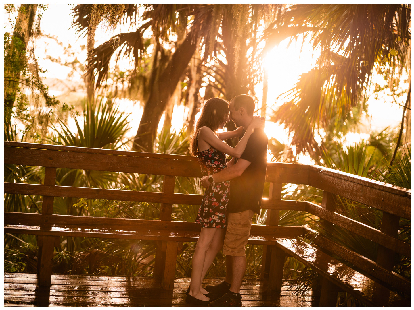 Couple kissing on a wooden bridge in warm evening light at Washington Oaks Gardens State Park.