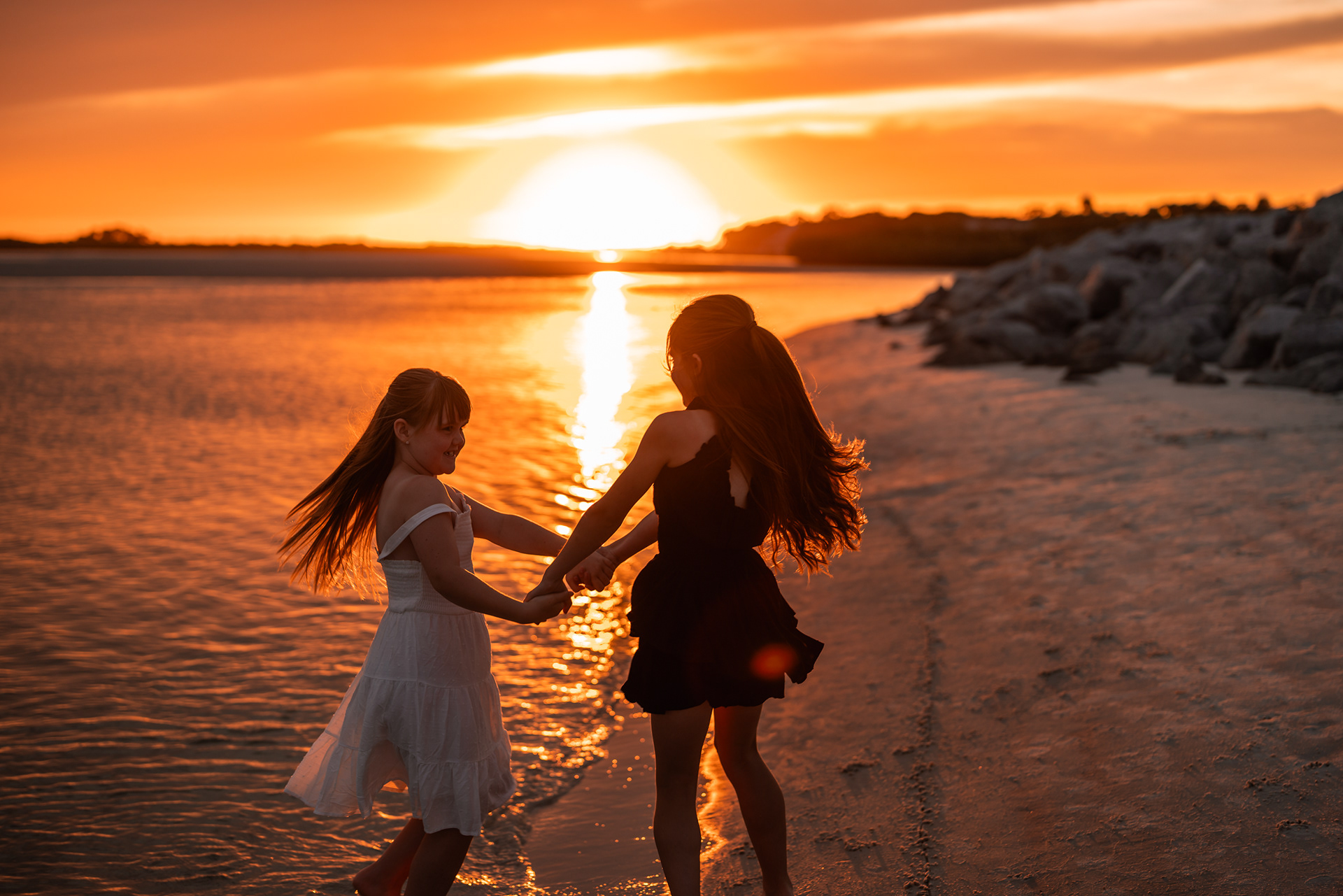 Sisters holding hands near the water during a Ponce Inlet Beach family photography session.