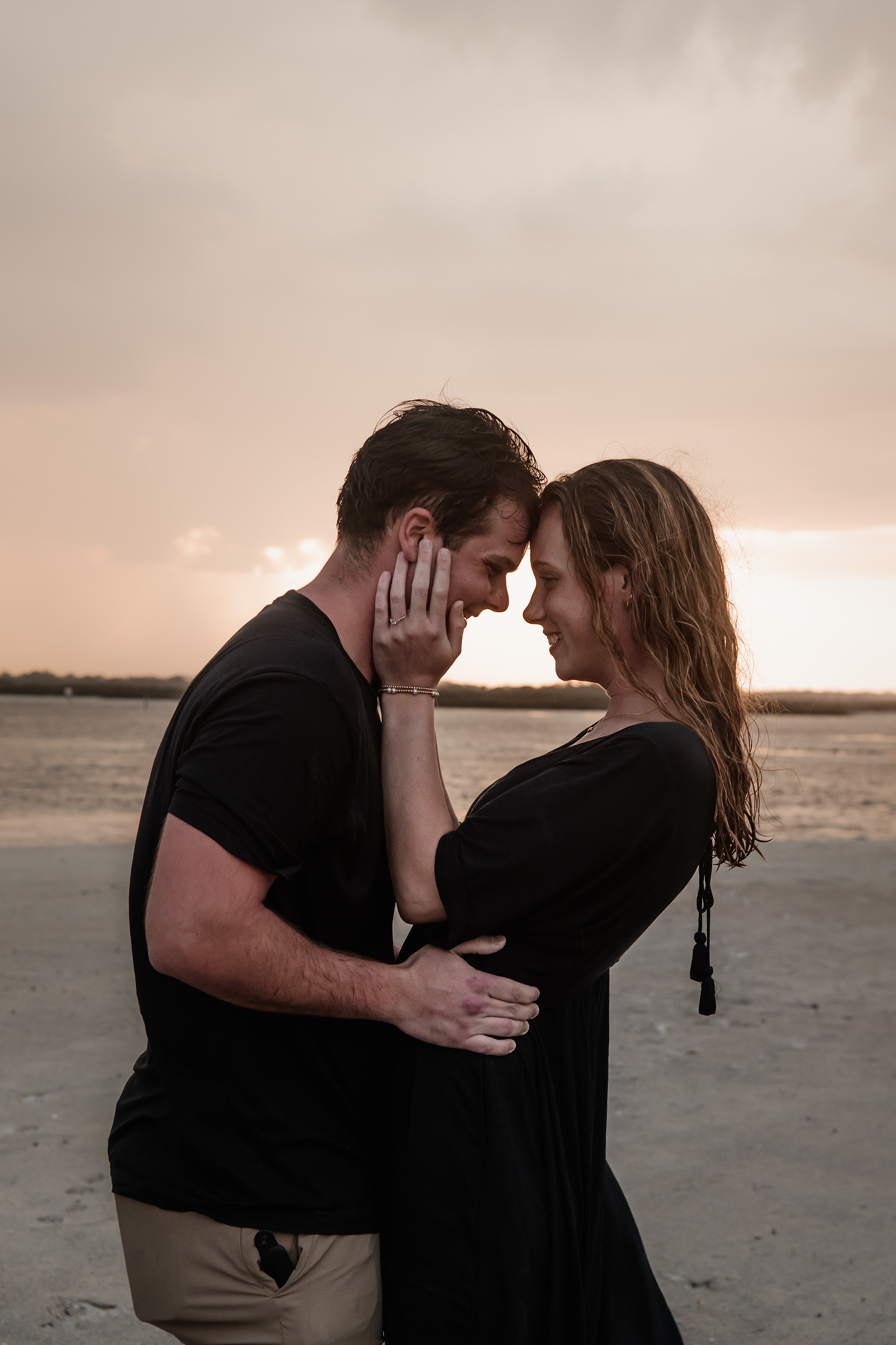 Close-up romantic beach engagement photo of couple embracing at Ponce Inlet