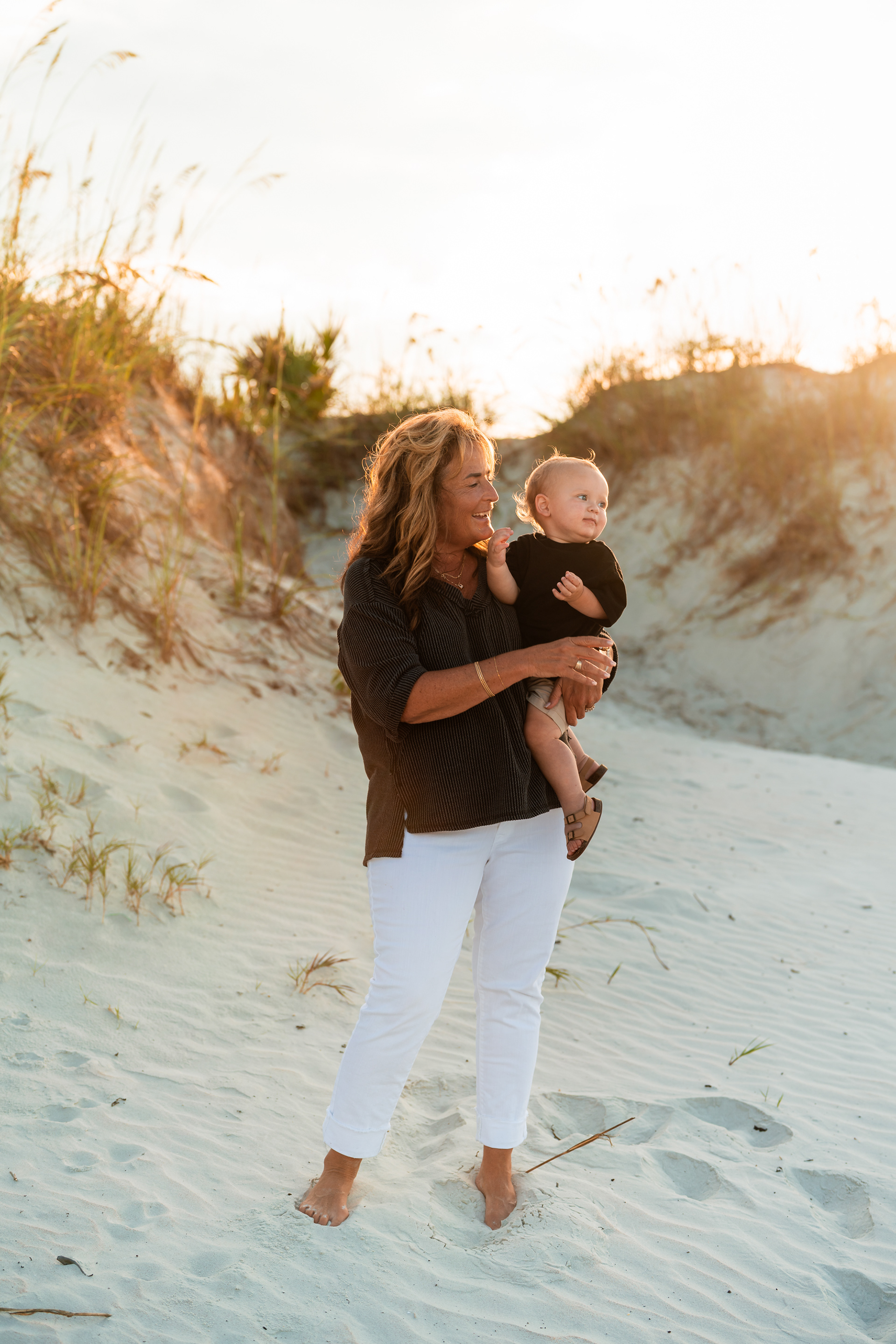 Woman holding a child near the dunes during a sunset family photo session in Ponce Inlet.