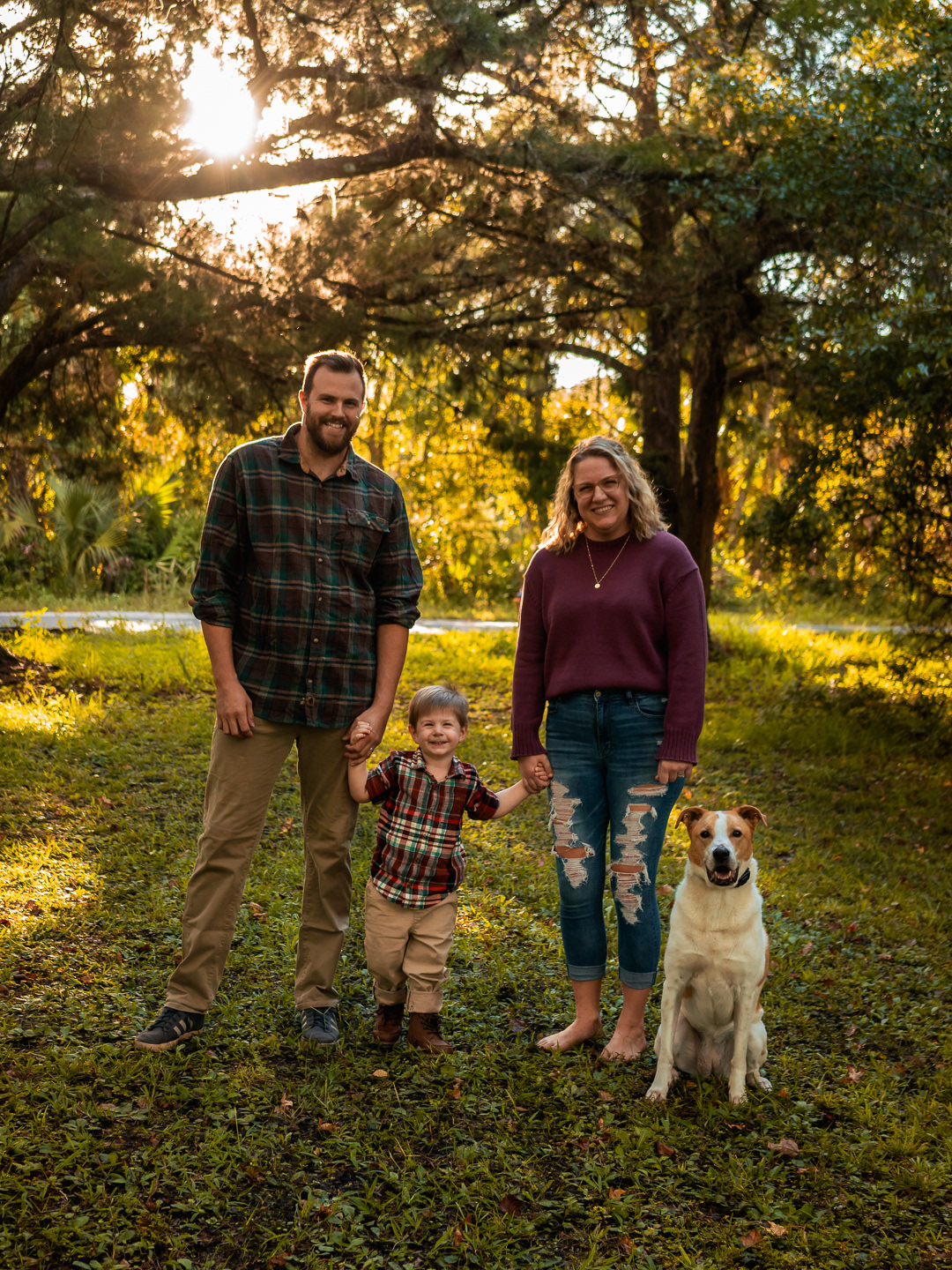 Family portrait in New Smyrna Beach, Florida with Jon, Sarah, and their son David standing together with their dog during golden-hour backyard photos.
