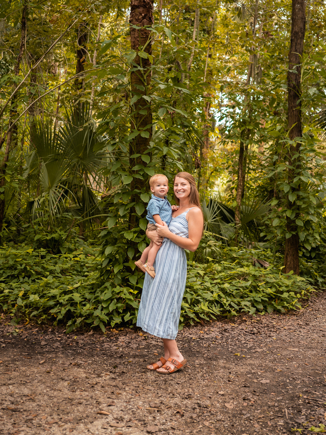 Mother holding her son and smiling during a warm and relaxed family photo session in the gardens.