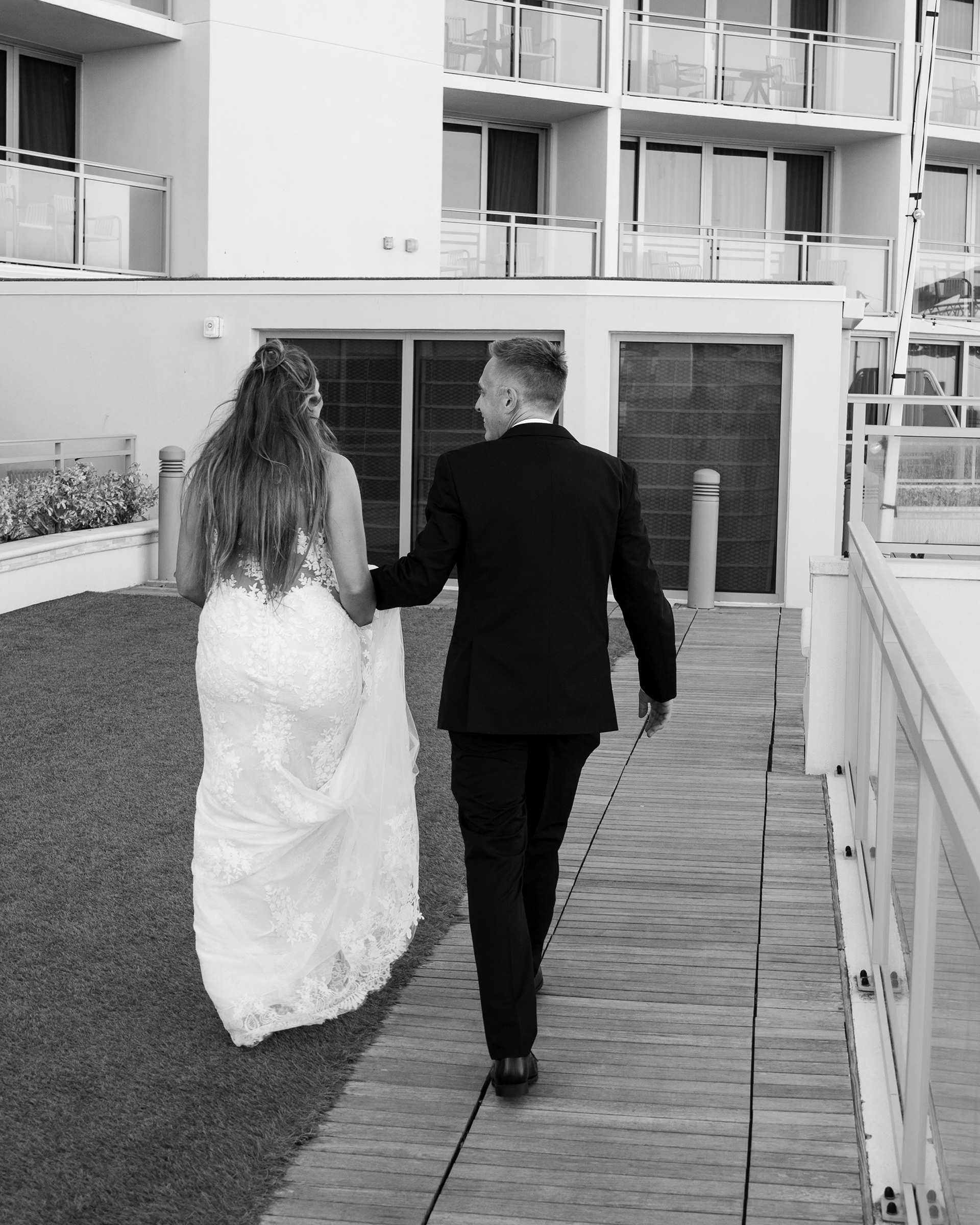 Black and white photo of the bride and groom walking together outside Hard Rock Hotel Daytona Beach.