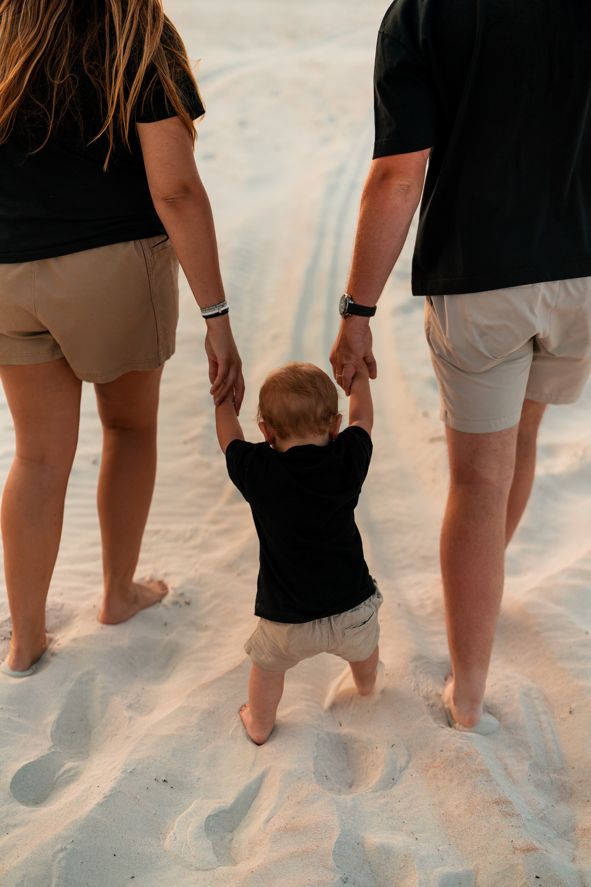 Parents walking with their toddler on the sand during a Ponce Inlet Beach family photo session.