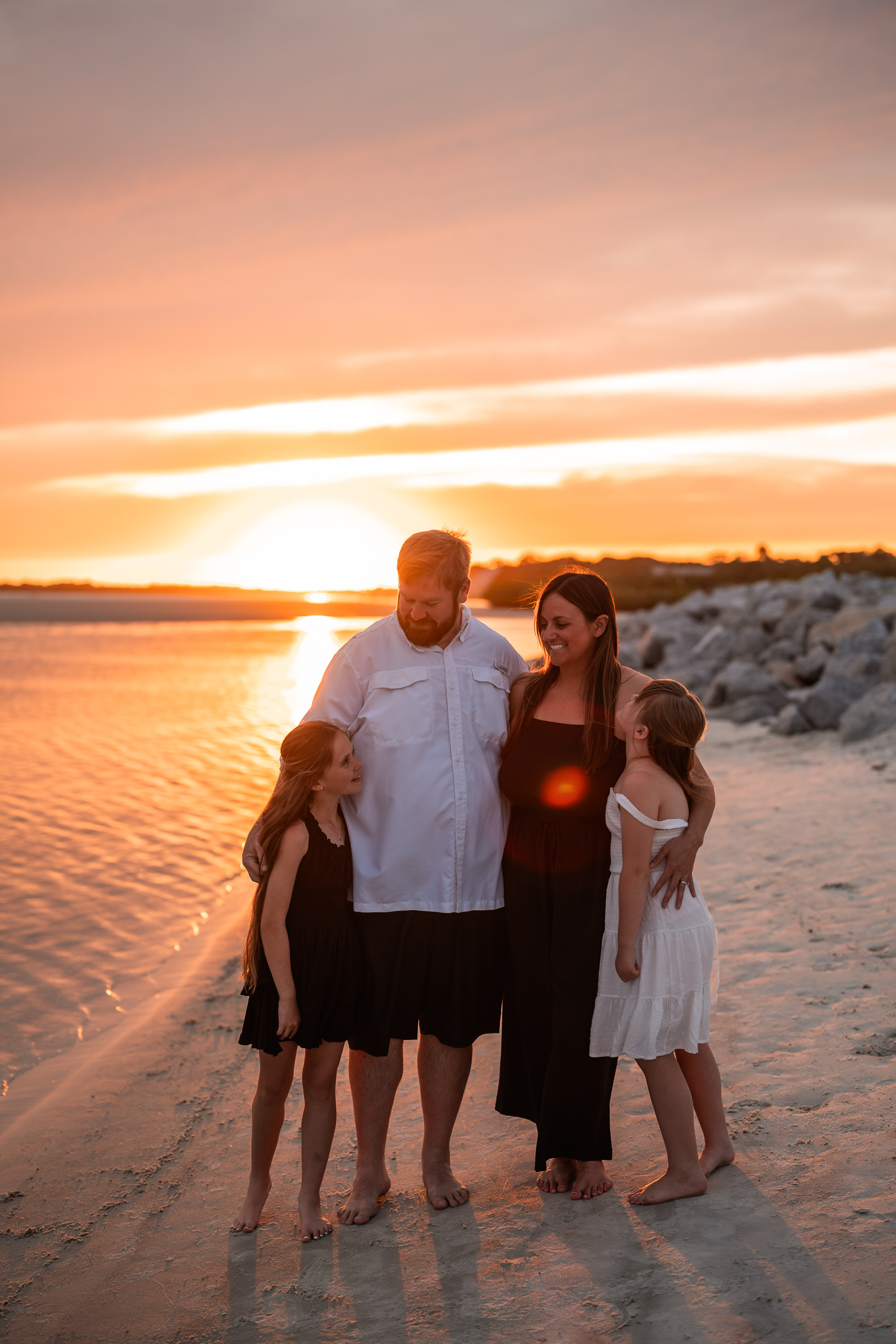 Family standing together on the beach at sunset during a Ponce Inlet family photo session.