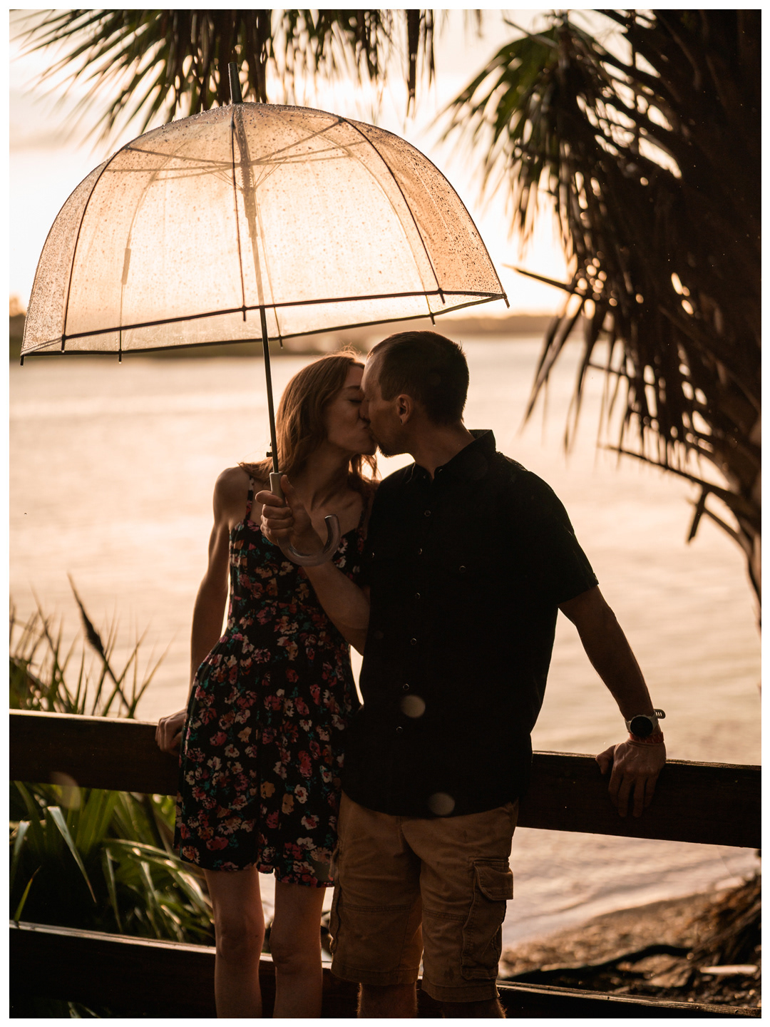 Couple kissing under a clear umbrella on a wooden overlook beside the Matanzas River at Washington Oaks Gardens.