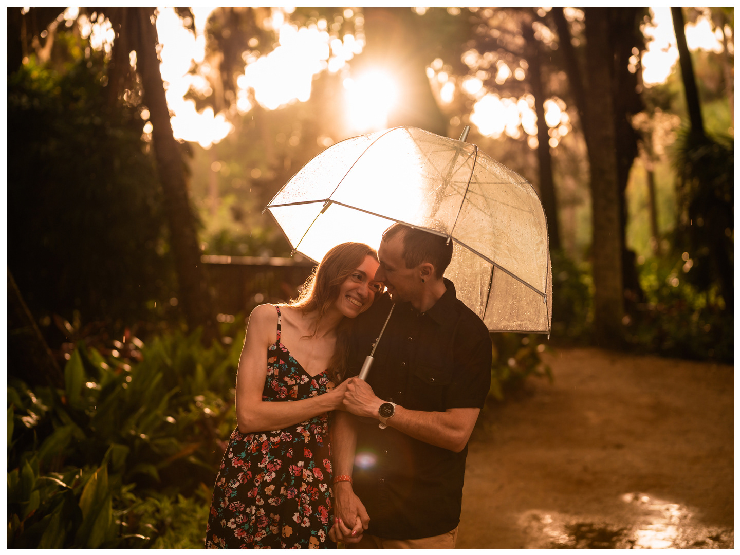 Woman resting her head on her partner beneath a clear umbrella during a rainy Washington Oaks photo session.