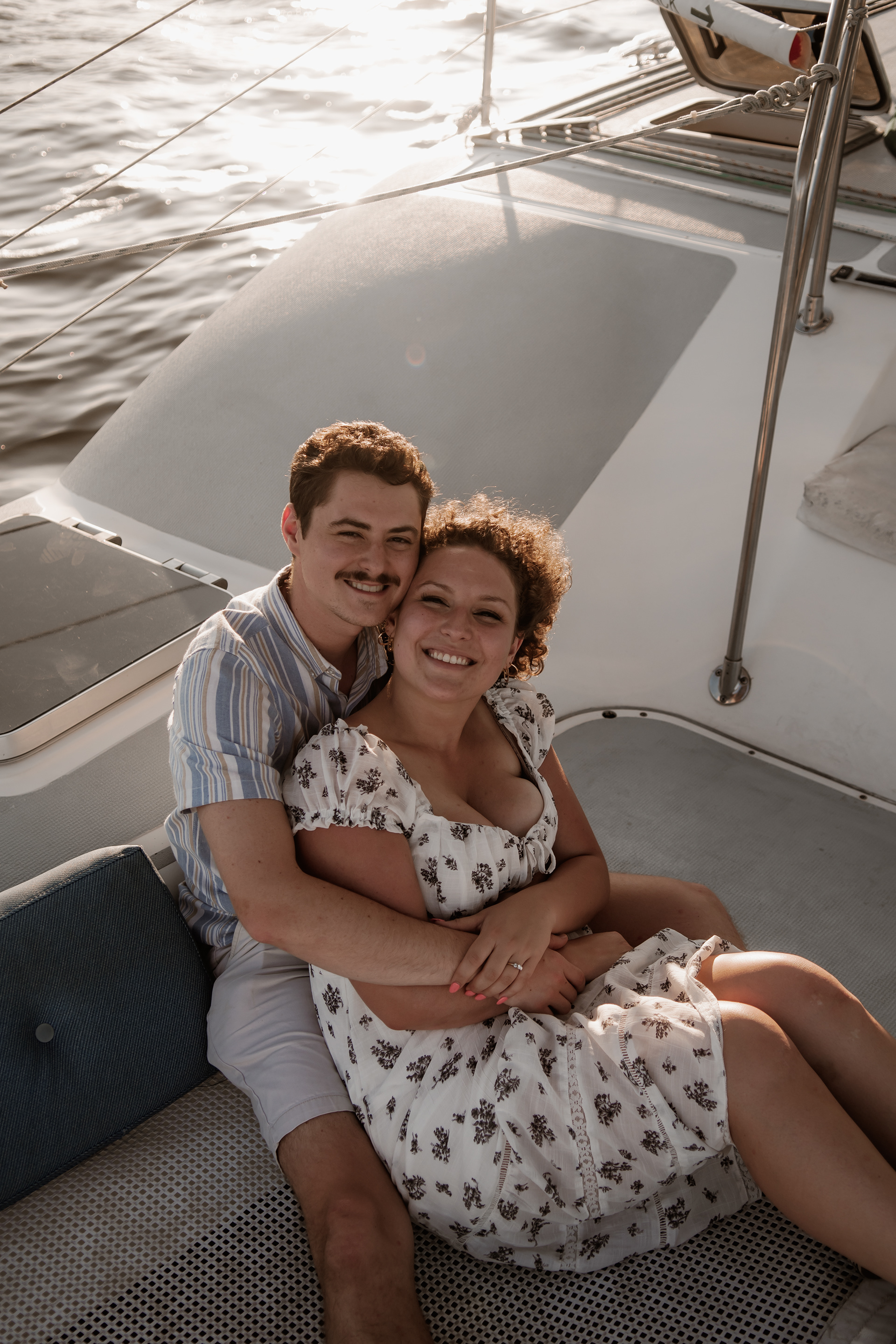 Couple cuddling on sailboat during romantic engagement photos in Daytona Beach Florida