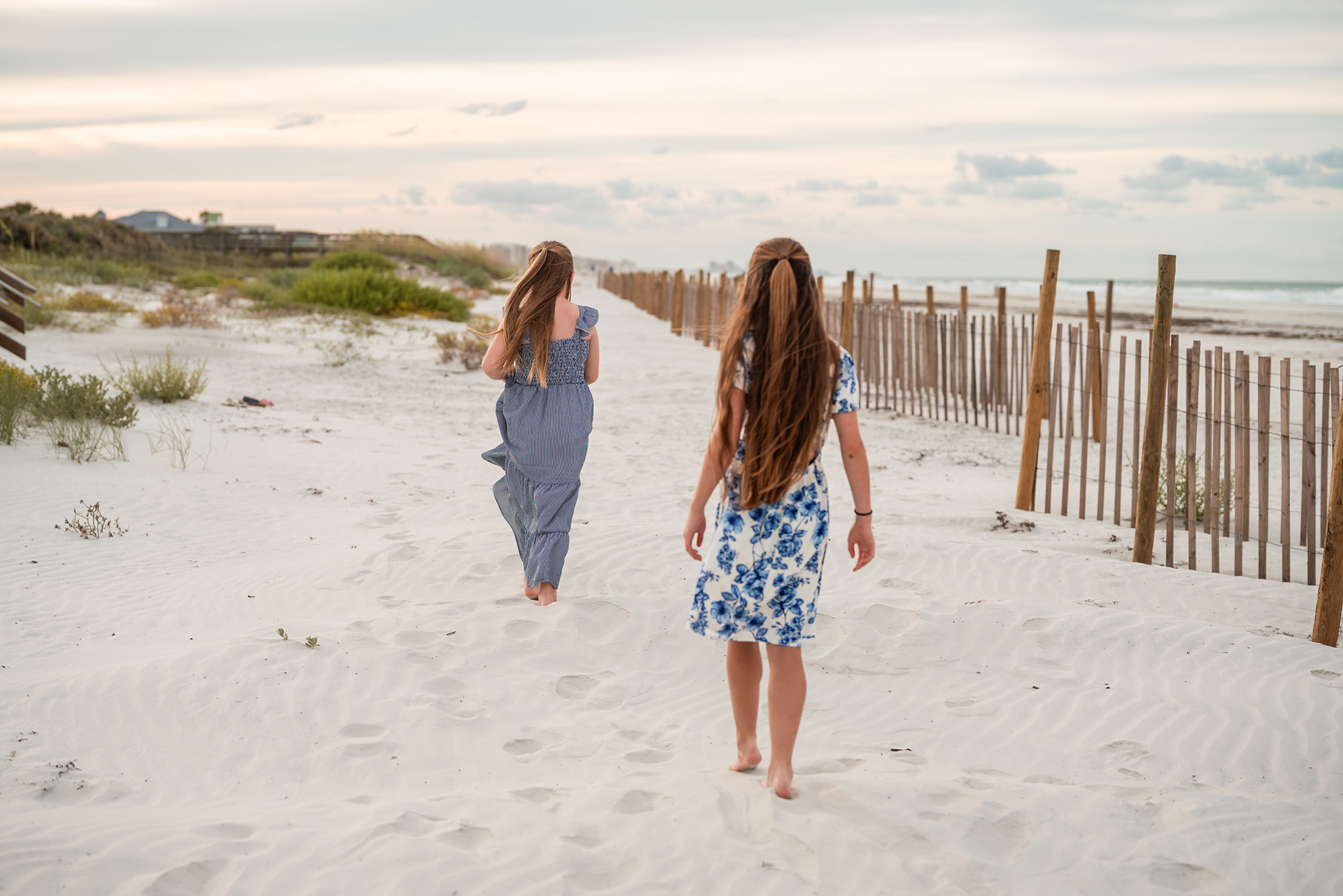 Two girls walking through the beach dunes during a Ponce Inlet family photography session.