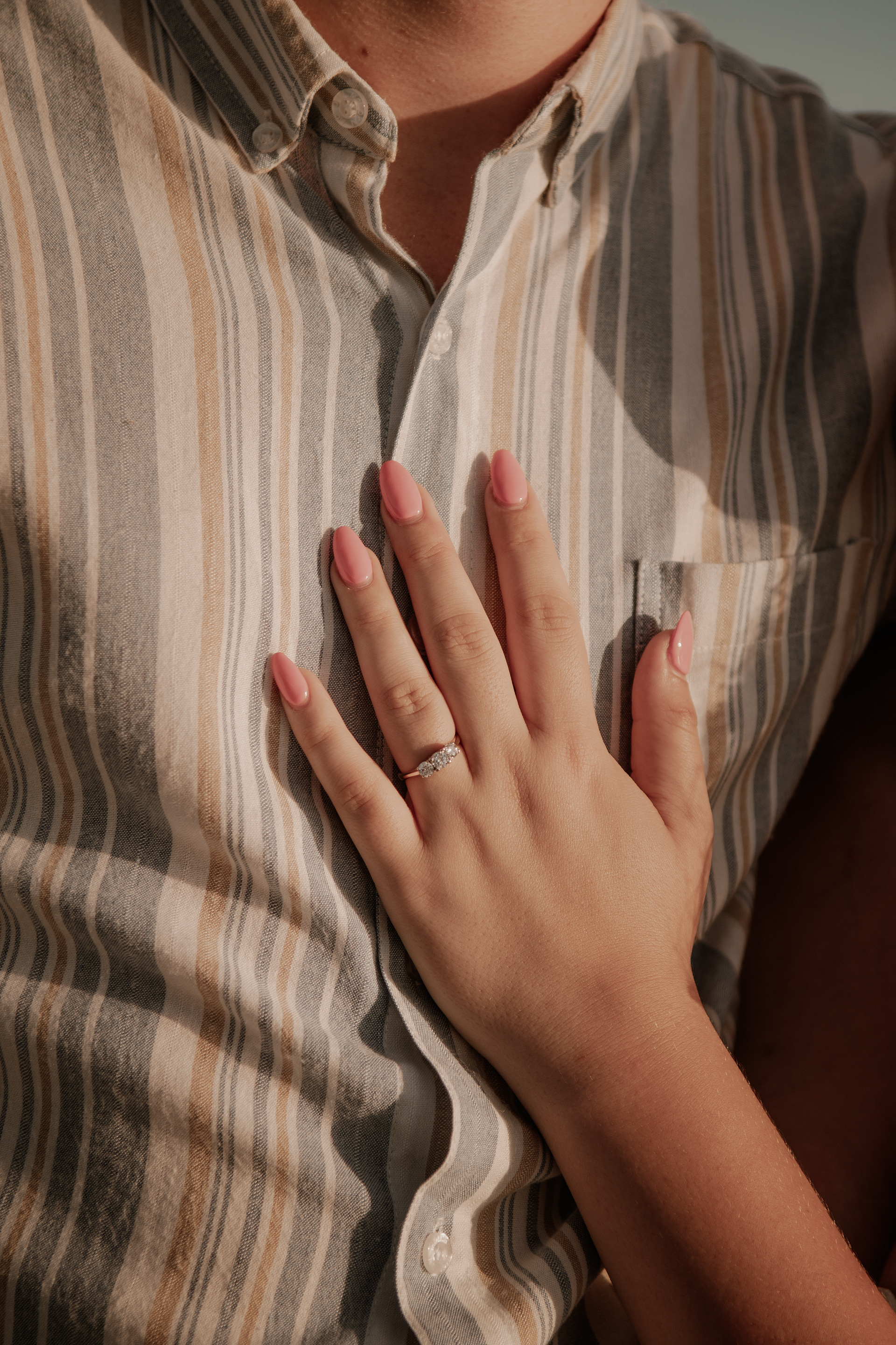 Close-up engagement ring photo with hand on striped shirt during sailboat engagement session