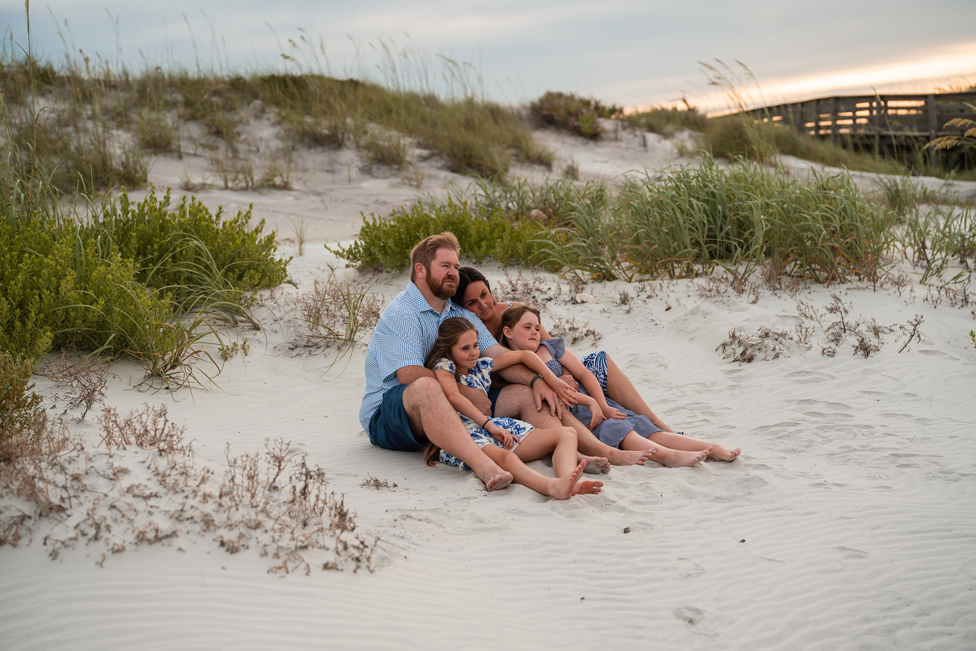 Family sitting together in the sand during a beach photography session in Ponce Inlet, Florida.