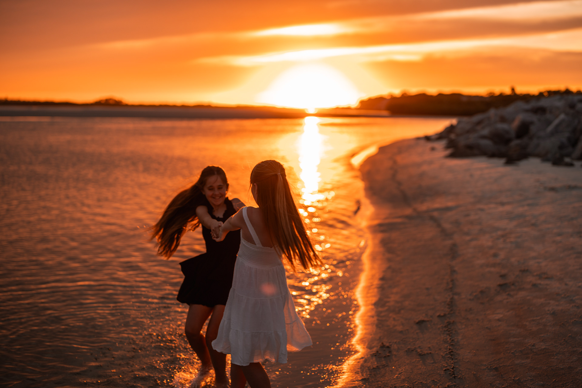 Two girls playing near the shoreline during a sunset family photo session at Ponce Inlet Beach.