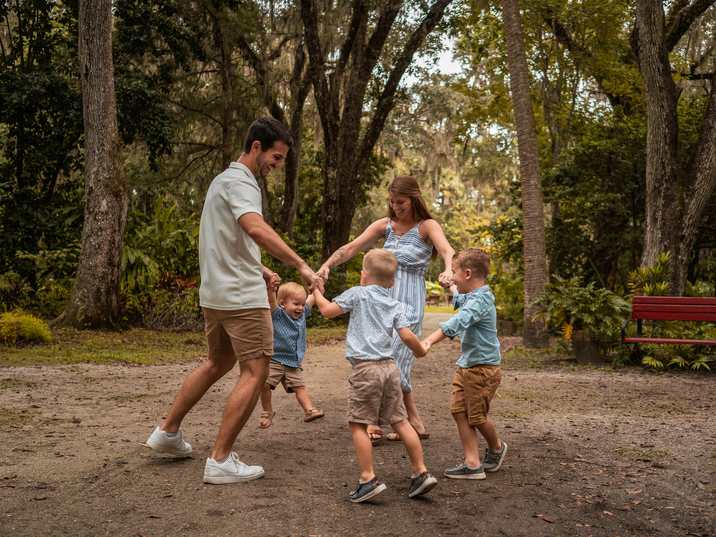 Family playing ring around the rosie together on a shaded path at Dunlawton Sugar Mill Gardens in Port Orange, Florida.
