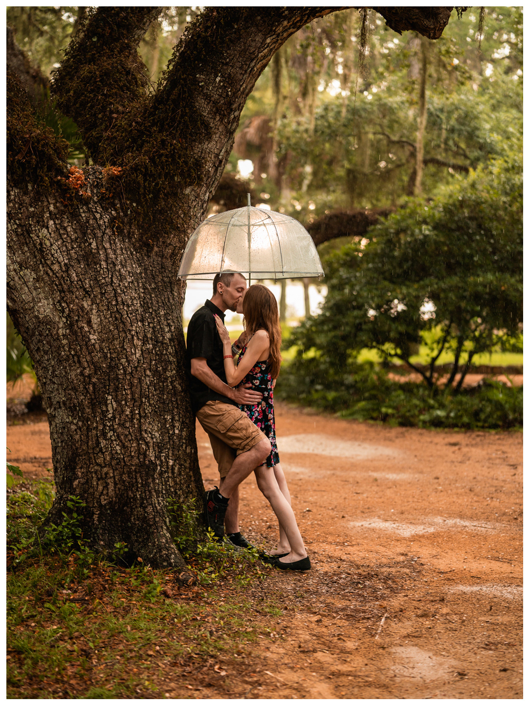 Full-length portrait of a couple embracing beside a sprawling oak tree at Washington Oaks Gardens.