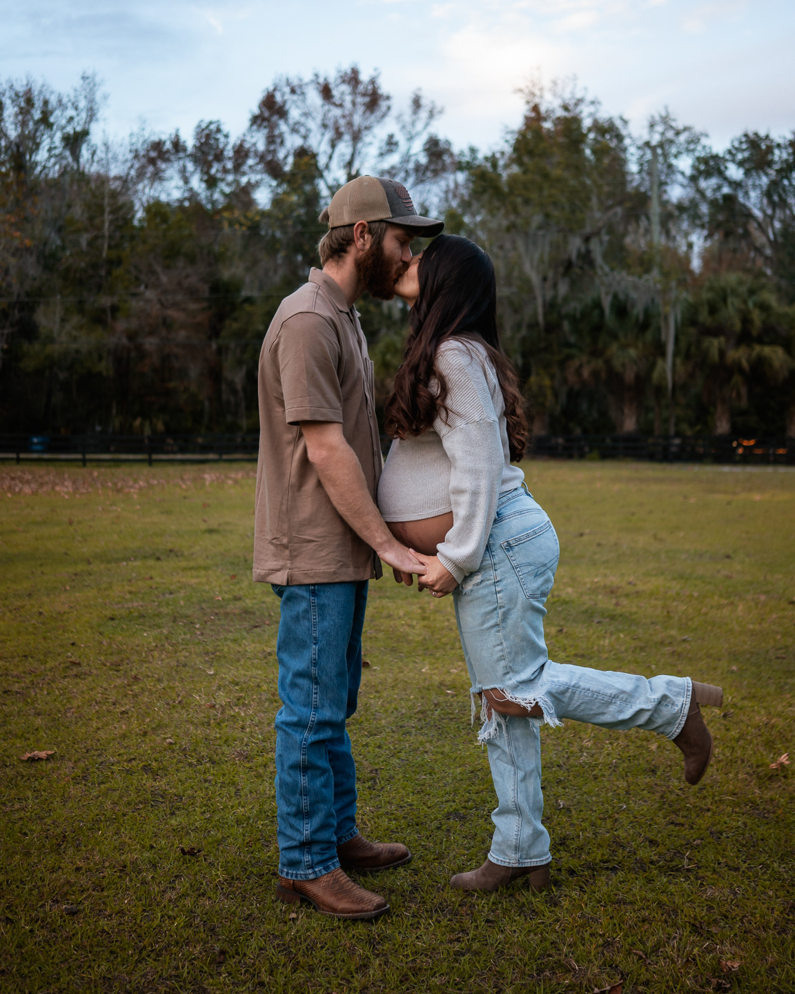 Father lifting child during outdoor maternity photos with pregnant mother
