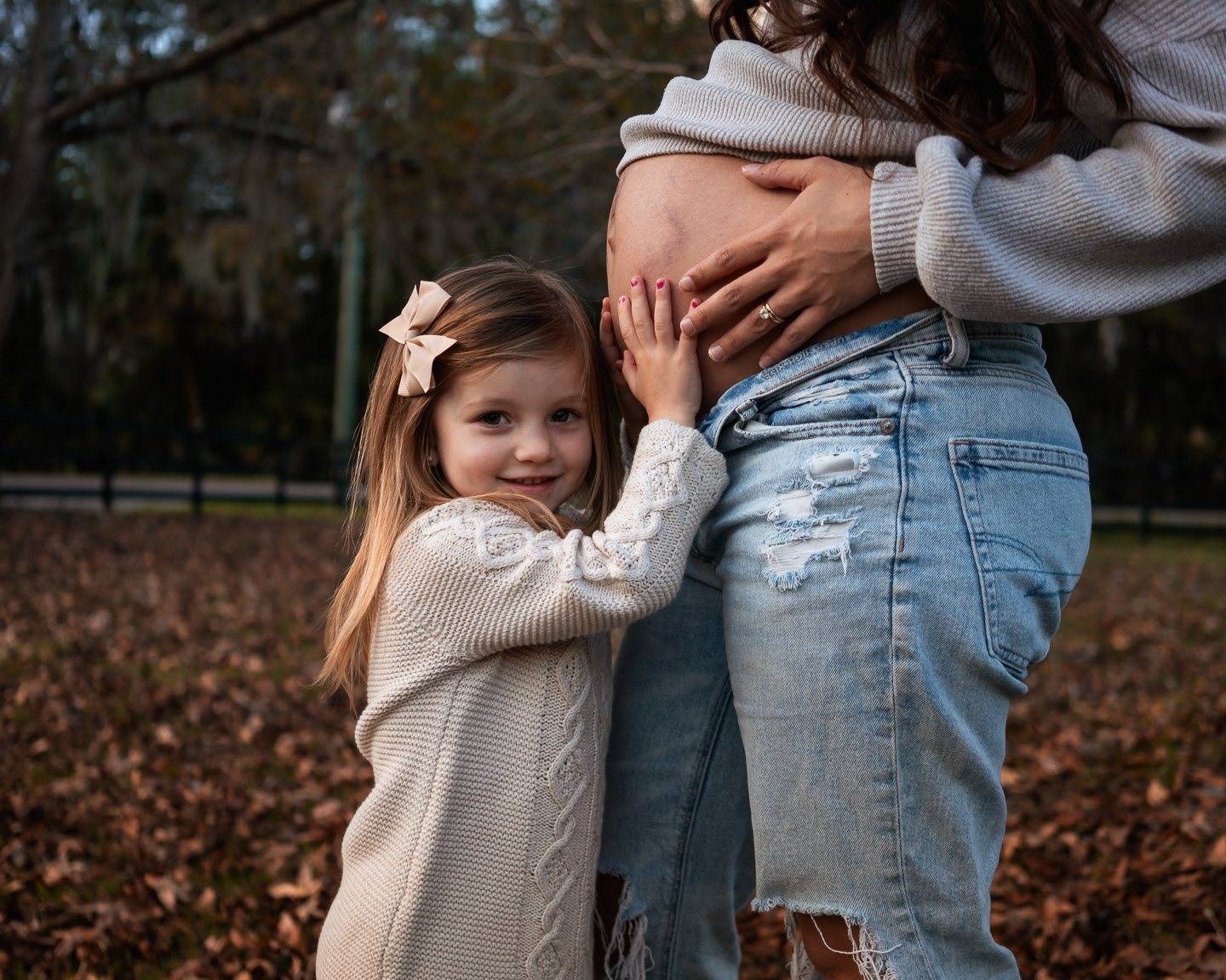 Child hugging mother’s baby bump during family maternity photo session
