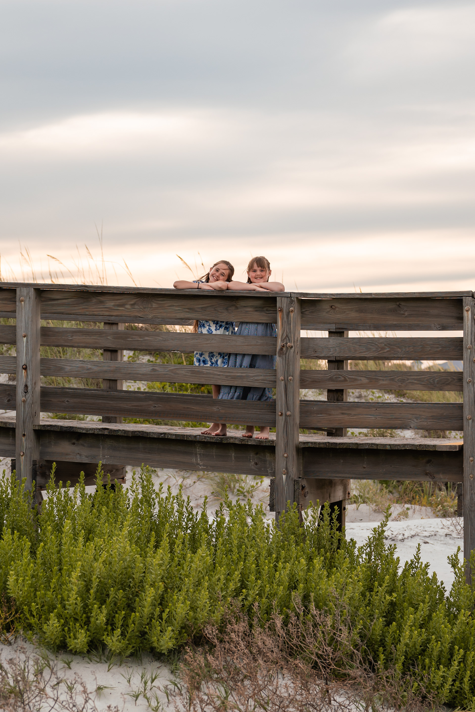 Family peeking over the boardwalk railing during a beach photography session in Ponce Inlet.