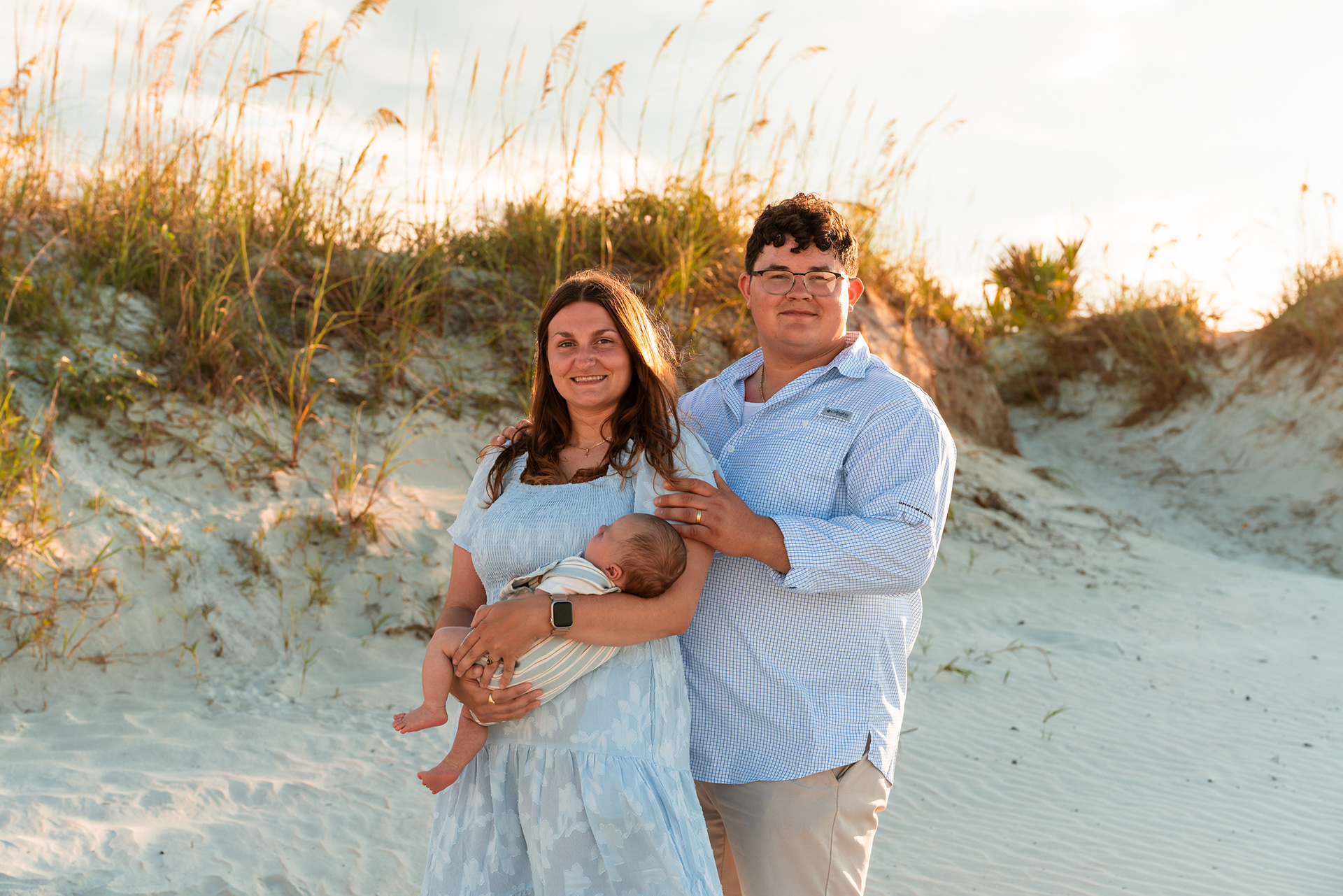 Parents holding their baby in the dunes during a Ponce Inlet Jetty Beach photo session.