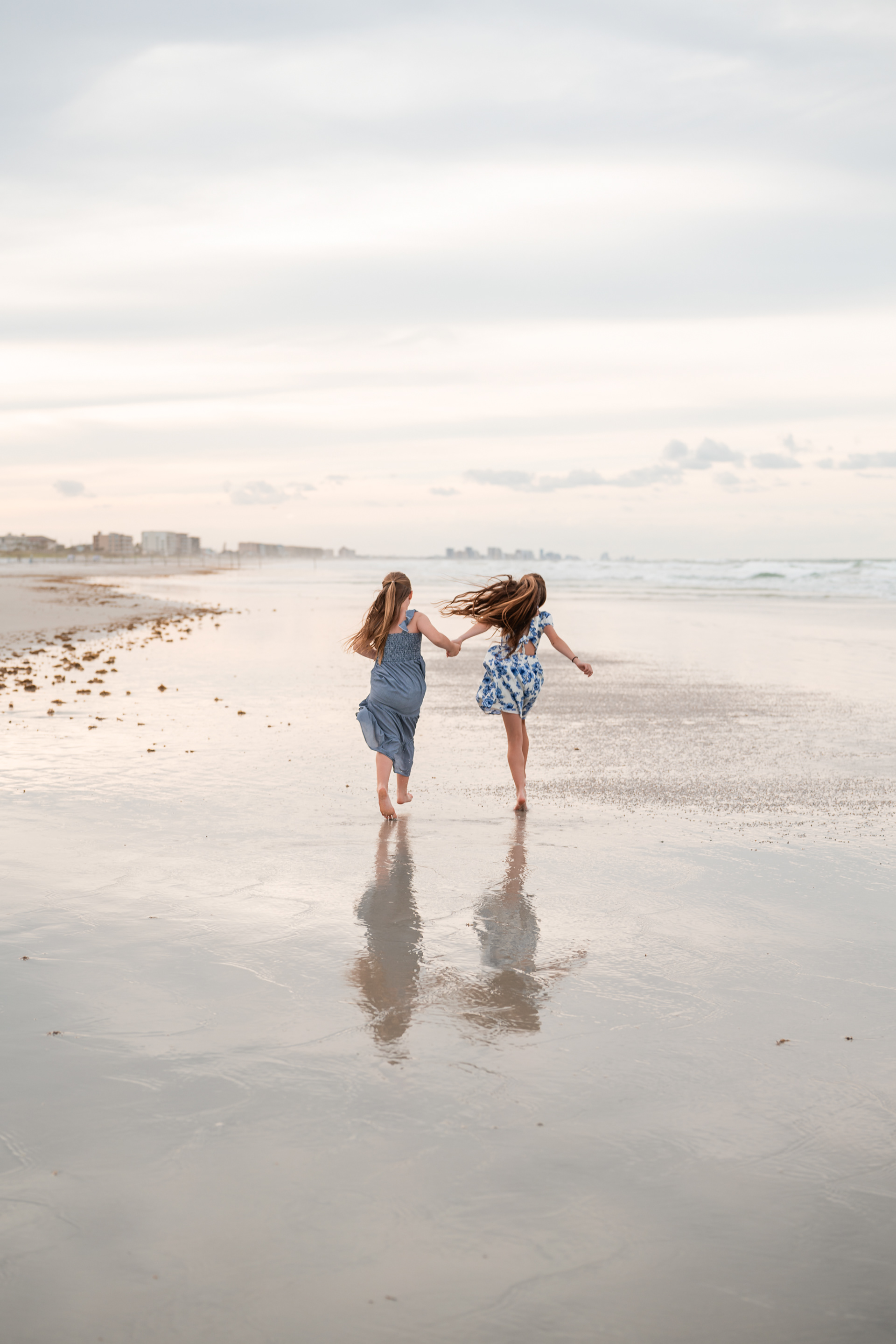 Two girls playing on the wet sand during a beach family photo session in Volusia County.
