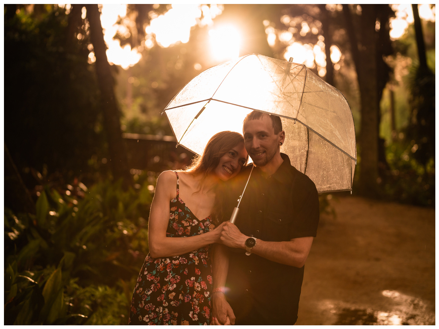Couple sharing a close moment beneath an umbrella with golden sunlight in the background at Washington Oaks Gardens.