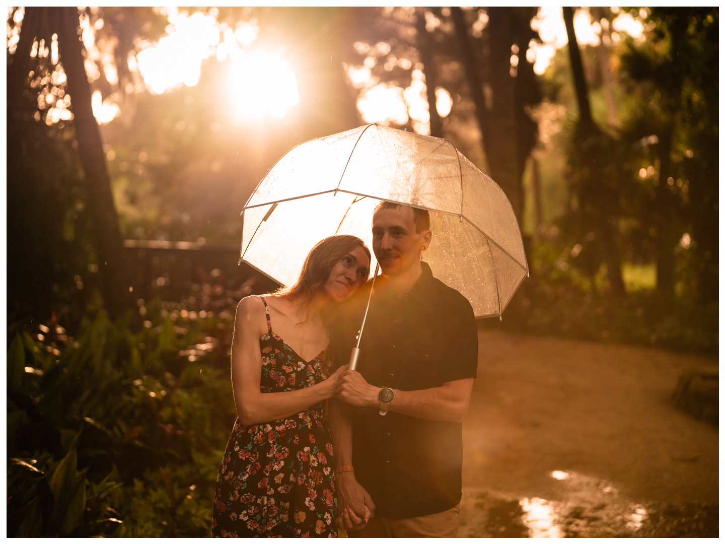 Woman resting her head on her partner beneath a backlit umbrella at Washington Oaks Gardens State Park.