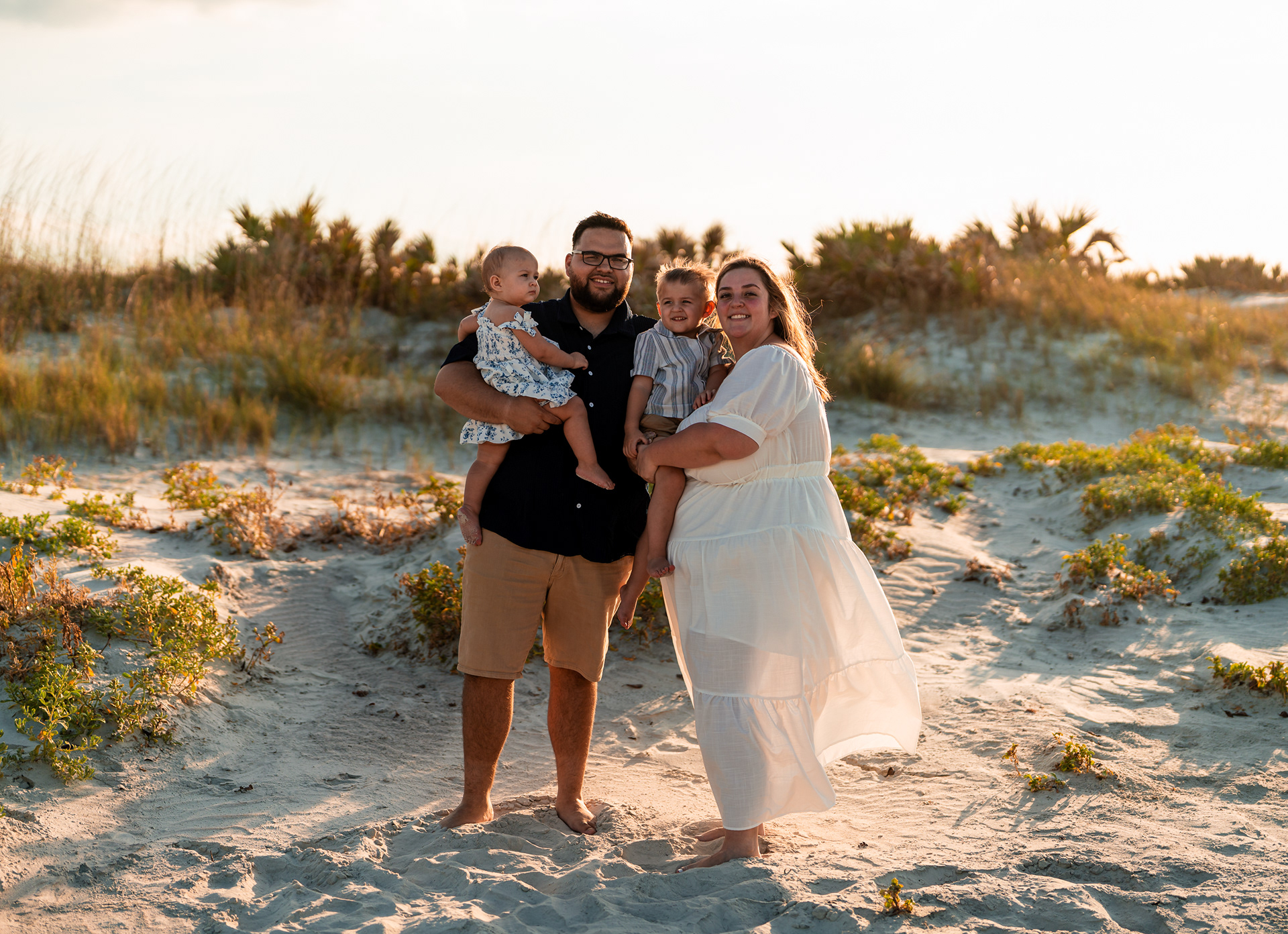 Family portrait at Ponce Inlet Beach with parents and children standing together in warm sunset light