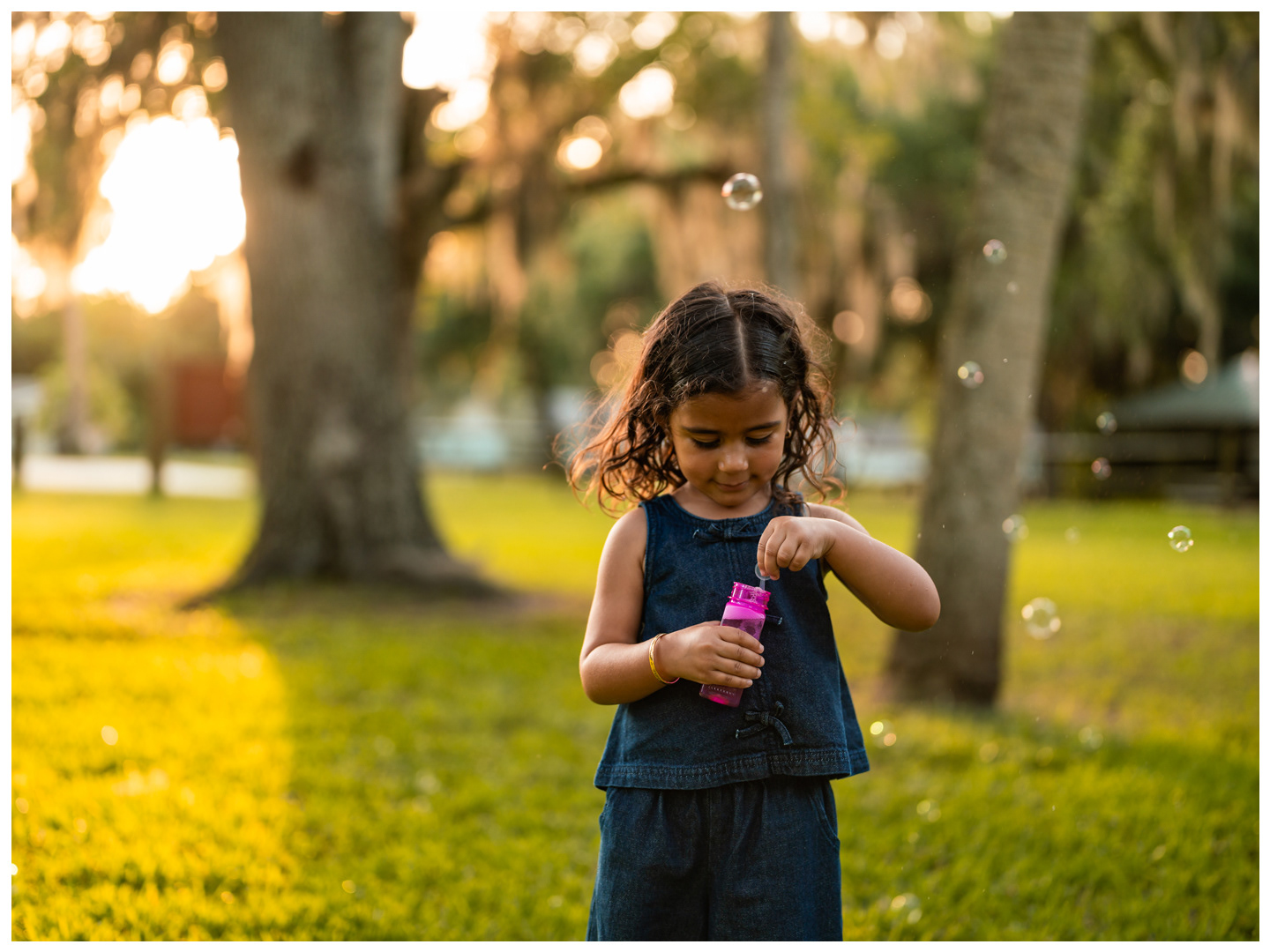 Girl blowing bubbles in warm sunset light at Buschman Park in Port Orange