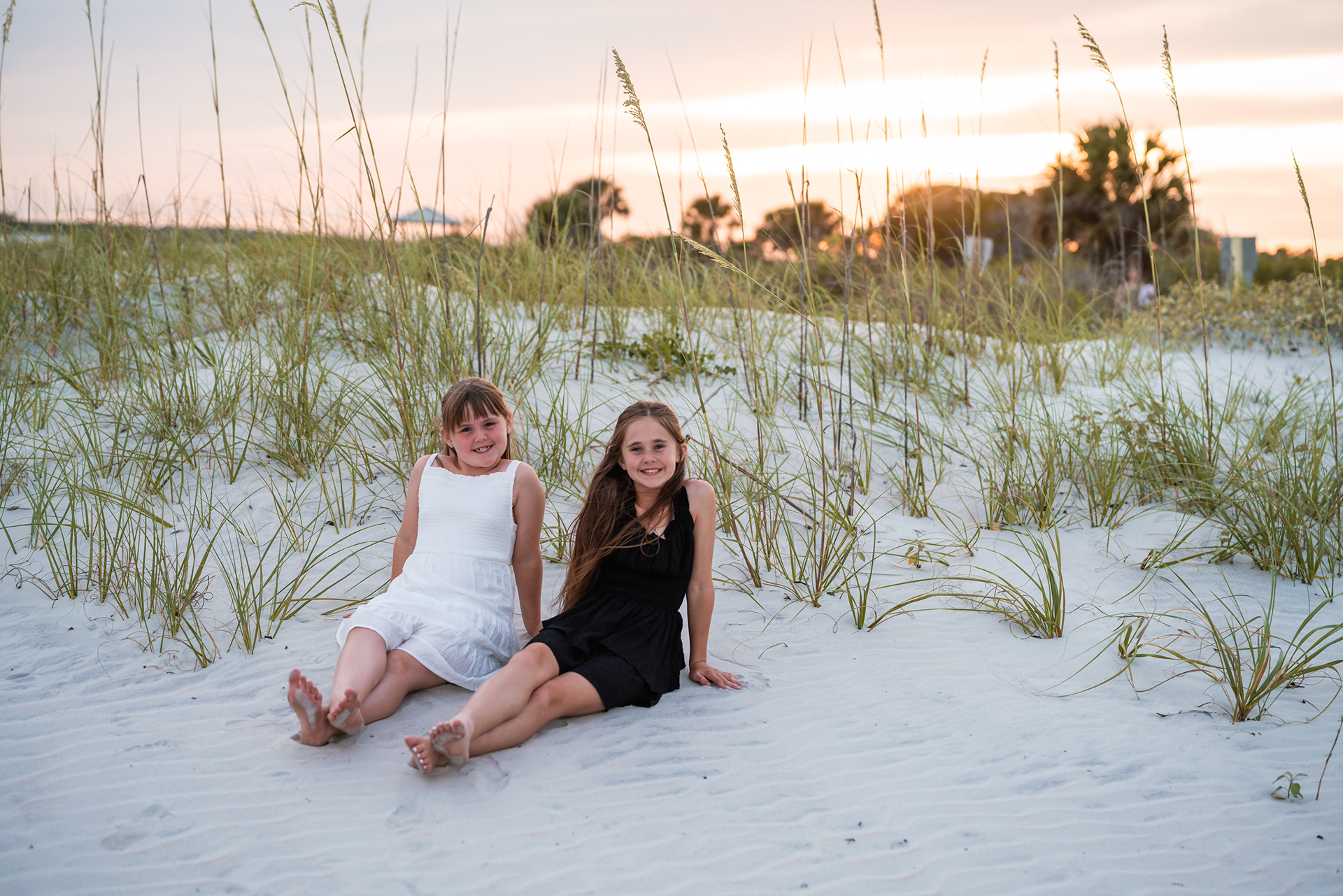 Two girls sitting in the dunes during a Ponce Inlet beach family photography session.
