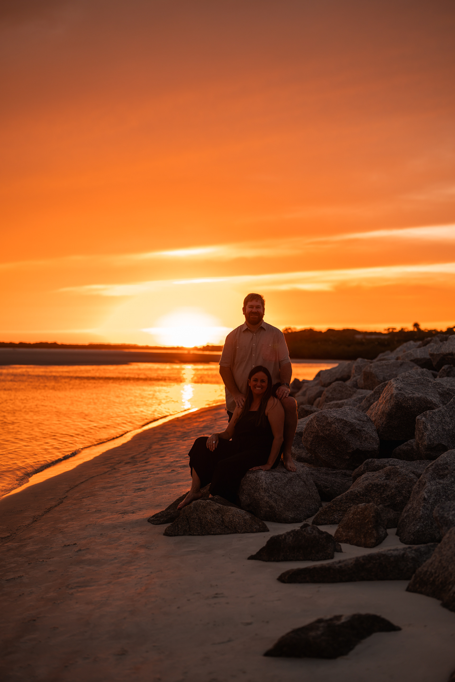 Family sitting near the rocks at Ponce Inlet Beach during a sunset photo session.