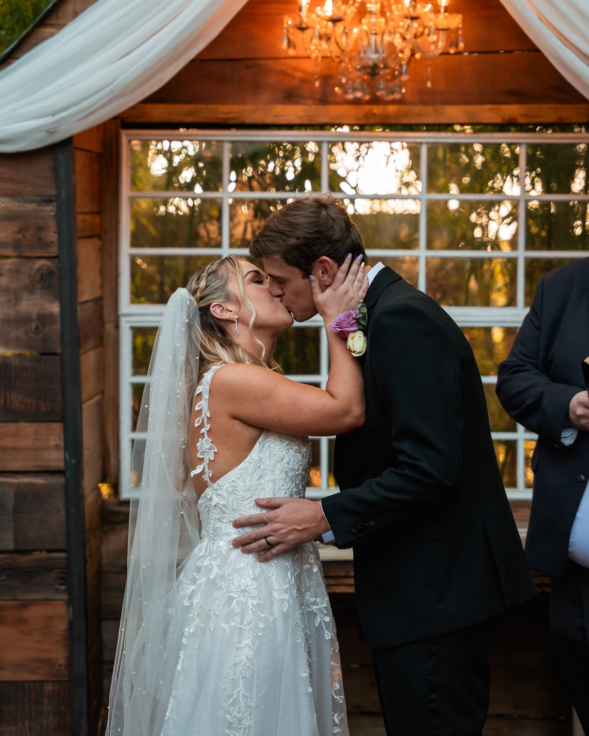 Bride and groom kissing in front of chapel window at Bridle Oaks Barn wedding