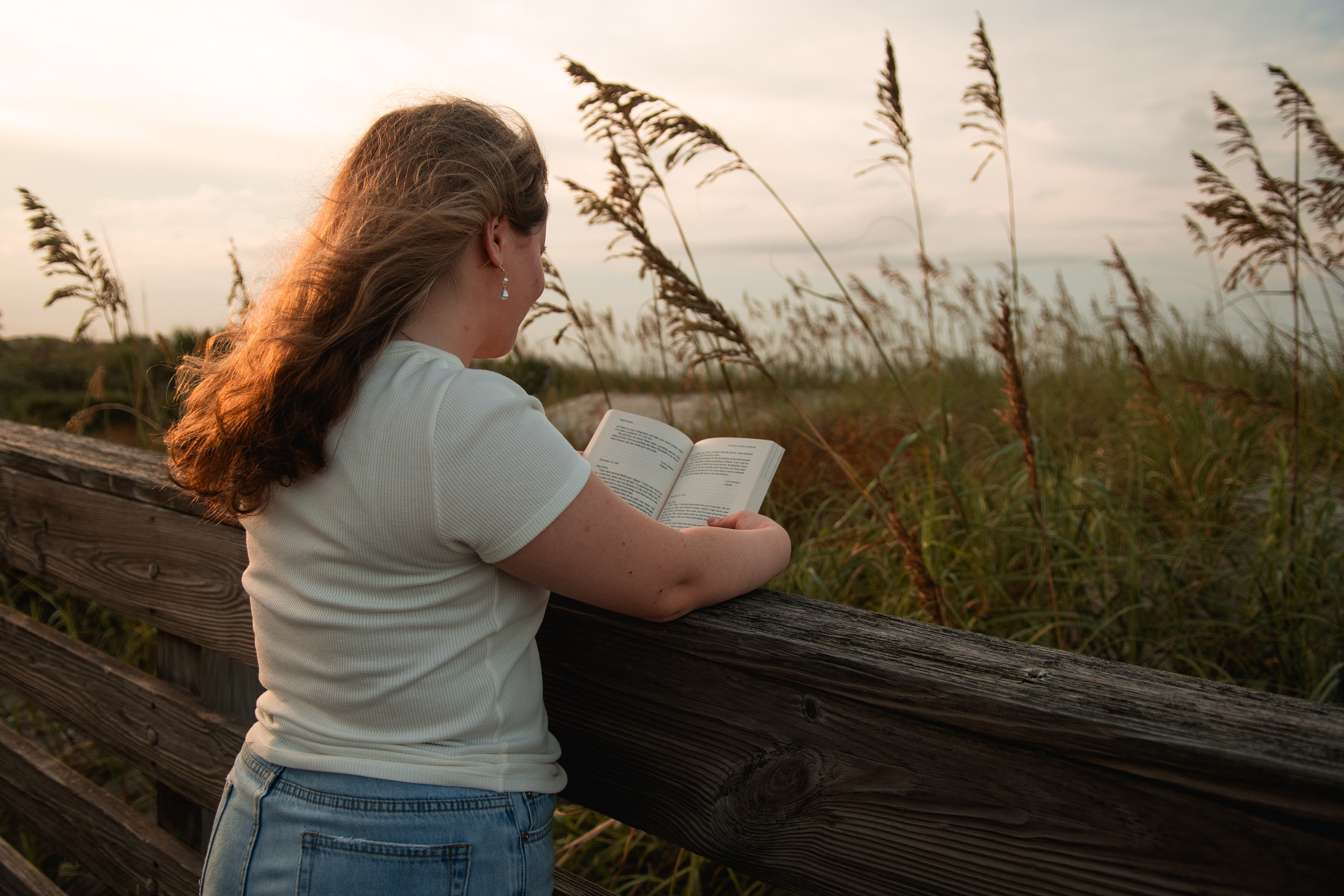 Senior photo on the boardwalk near Port Orange FL, Nelly facing the dunes with sunlight shining over her shoulder.