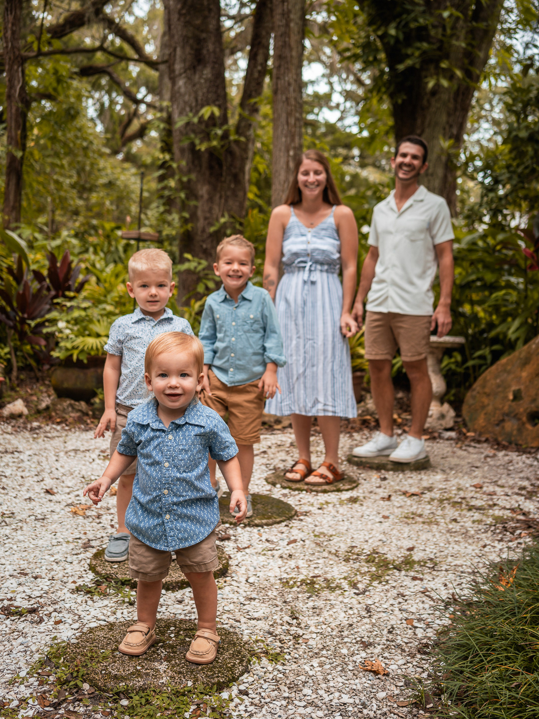 Family portrait at Dunlawton Sugar Mill Gardens in Port Orange Florida, the Rich family with young children and a toddler standing on a garden path surrounded by trees and greenery.