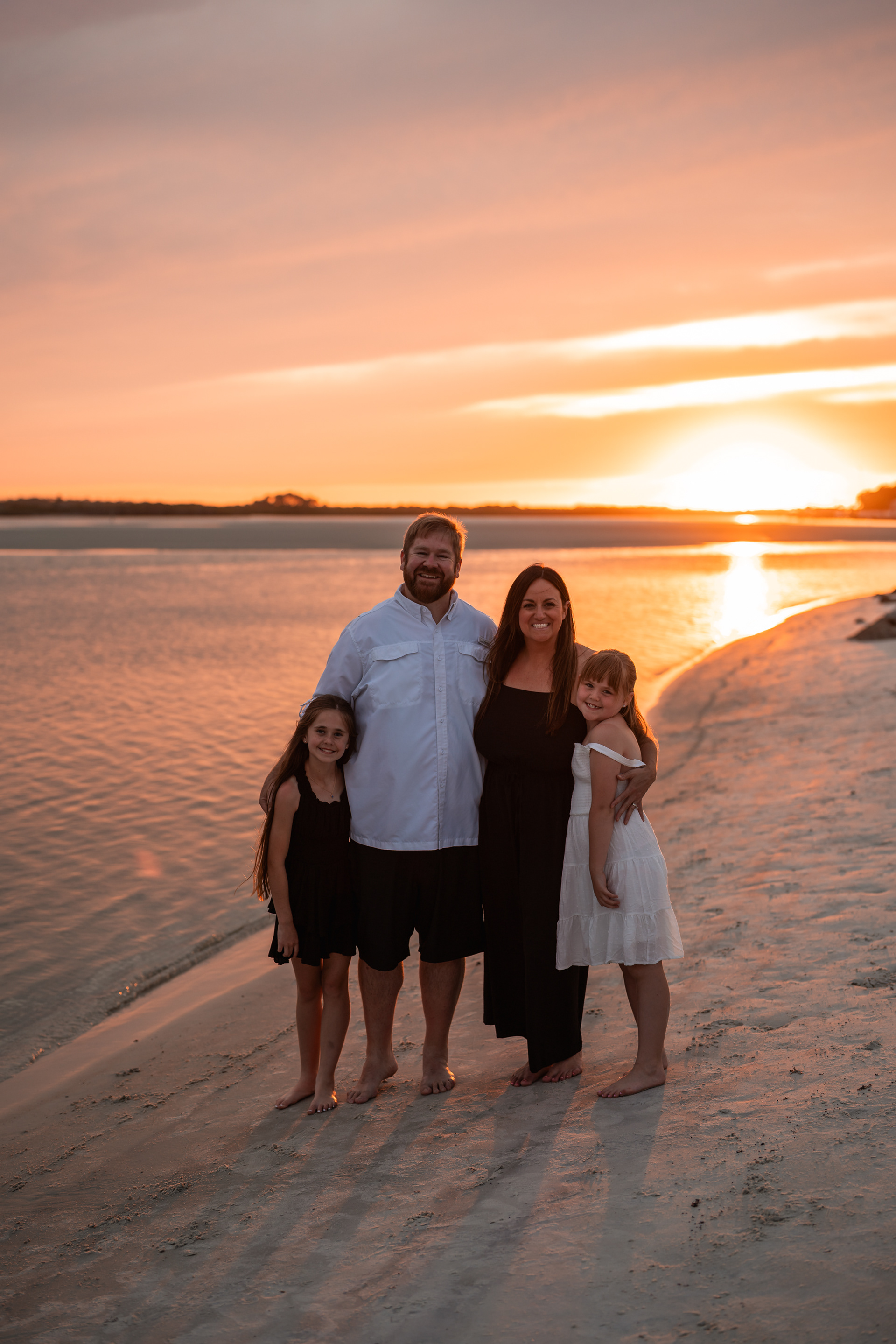 Family portrait on the sand with the sunset behind them at Ponce Inlet Beach.